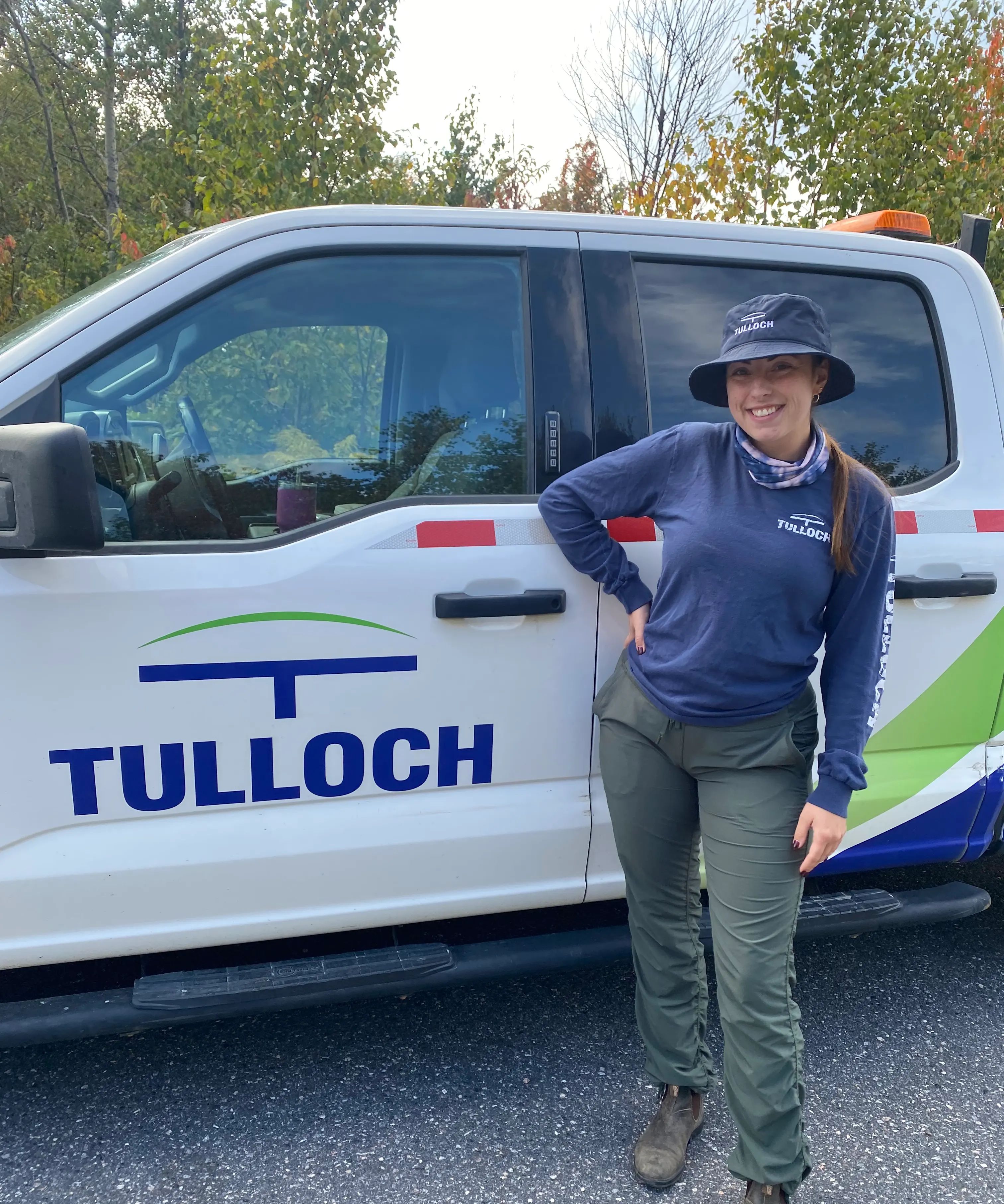 Environmental technician smiling in front of TULLOCH truck.