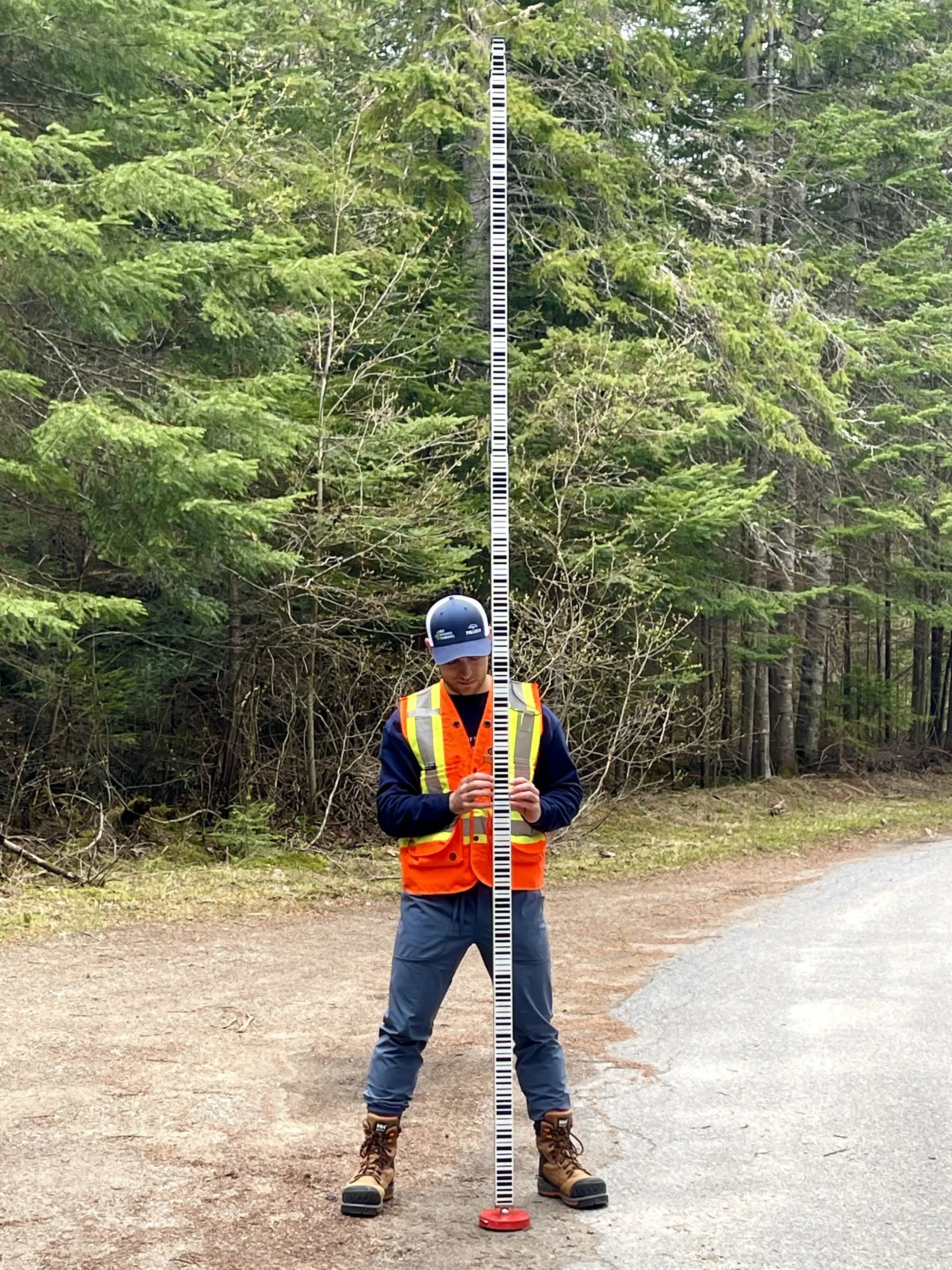 TULLOCH field technician operating survey equipment along a road.