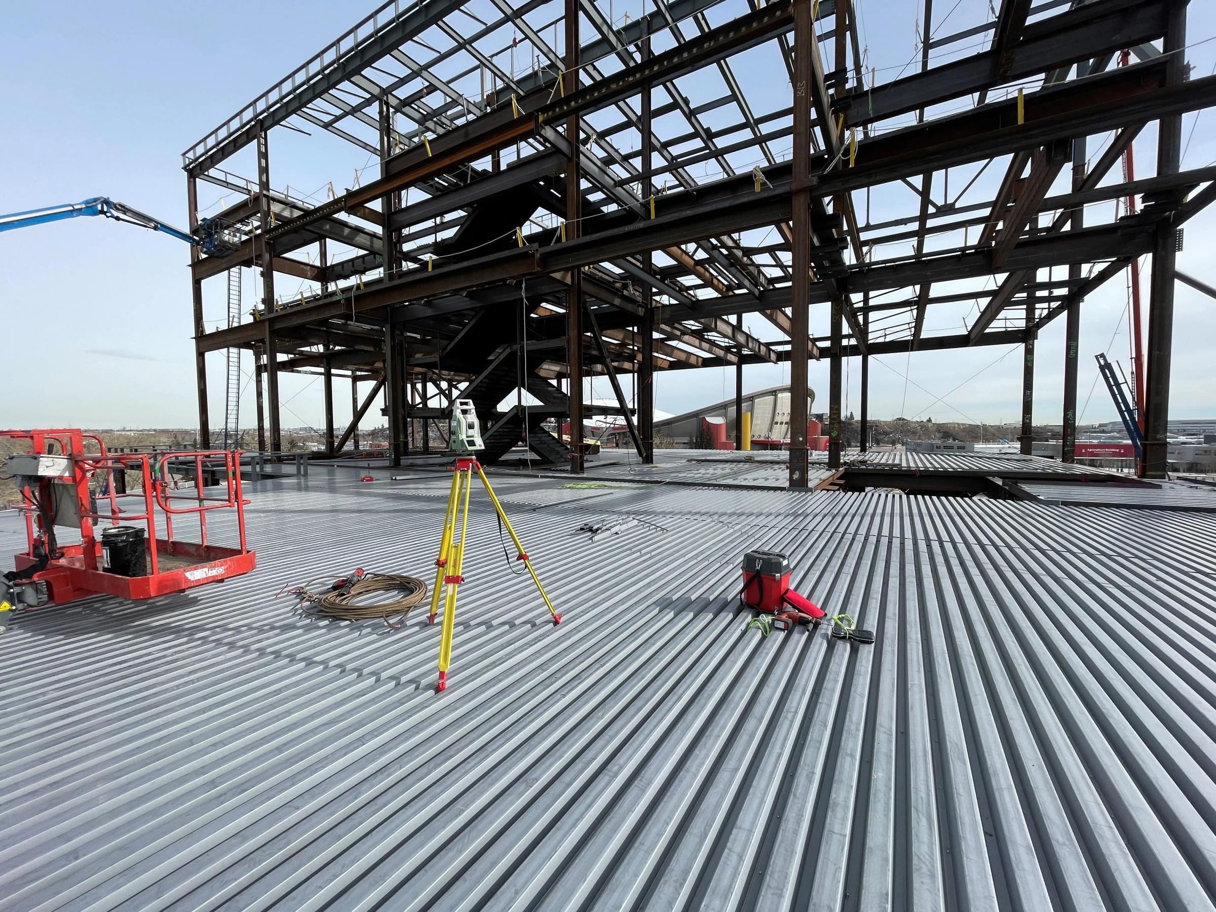 Survey equipment set up inside a steel-frame construction project.