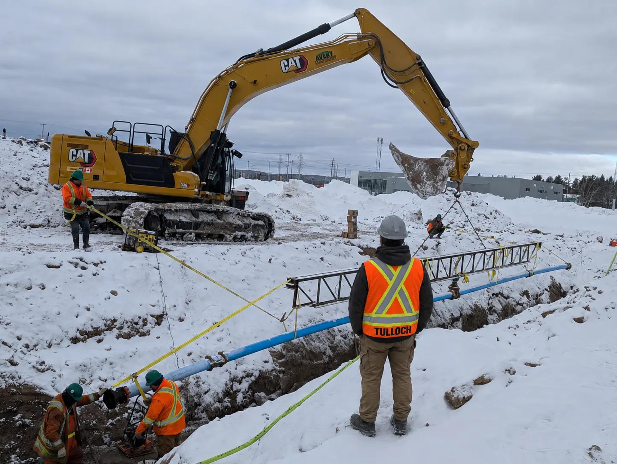 TULLOCH field technician observing active excavation during winter municipal construction.