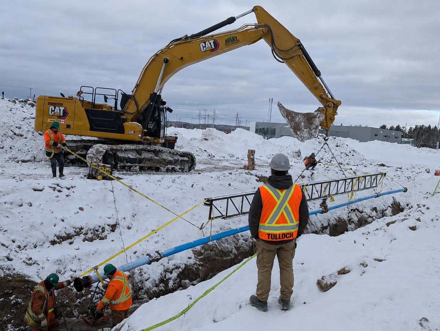TULLOCH field technician observing active excavation during winter municipal construction.