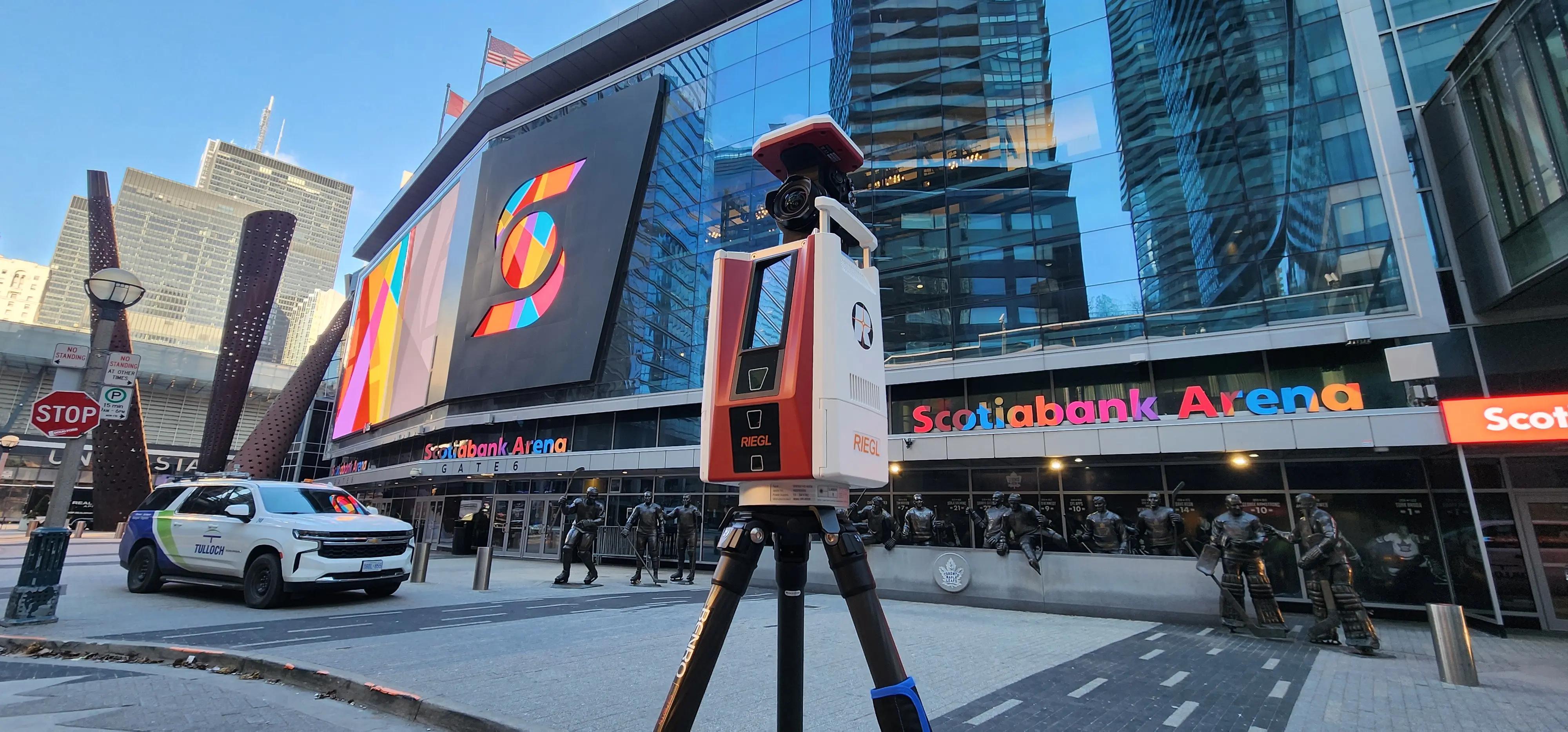 Static LiDAR scanner set up beside rail infrastructure in an urban station area.