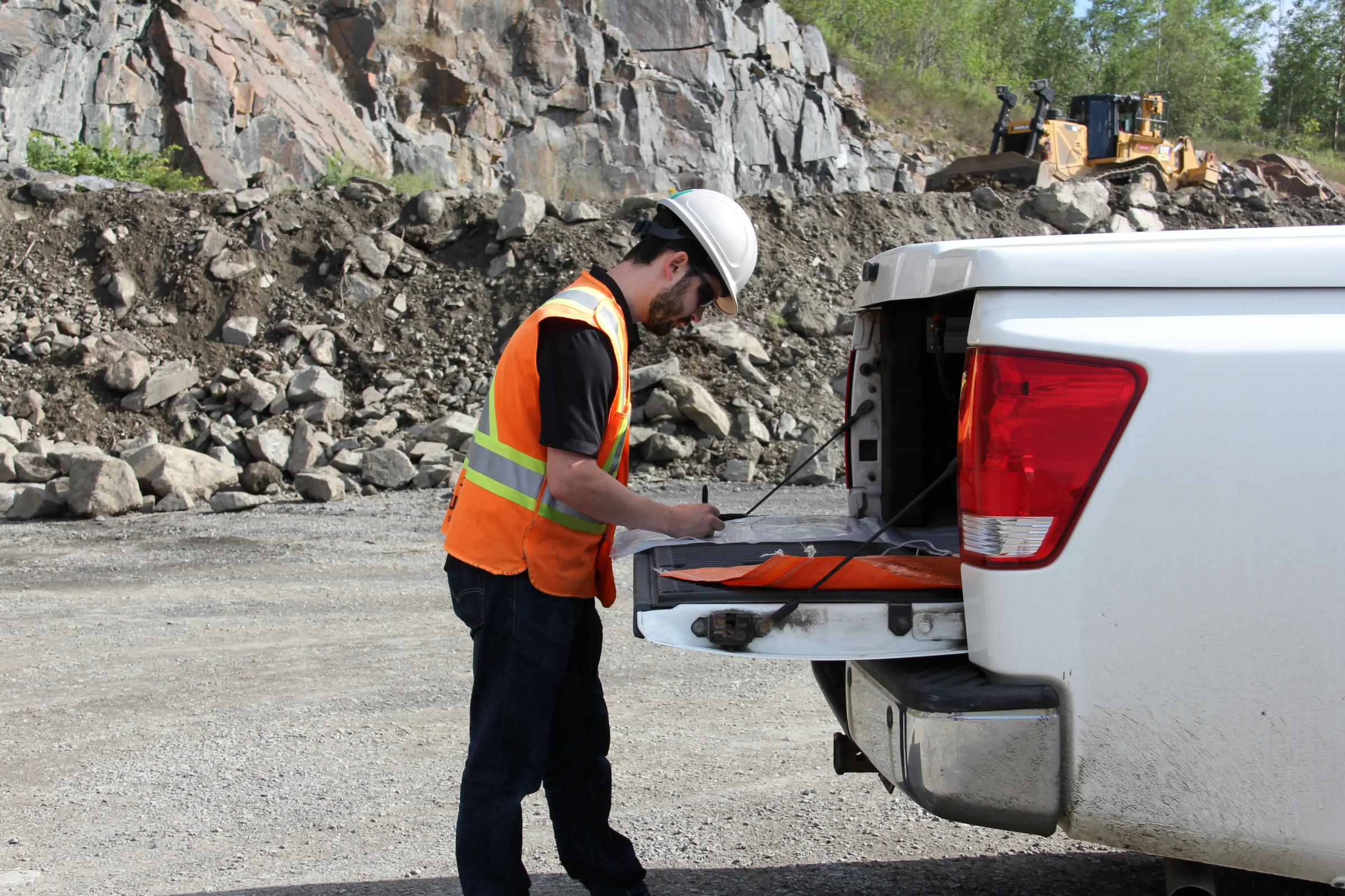 TULLOCH field technician working beside  a company truck near a rock cut.