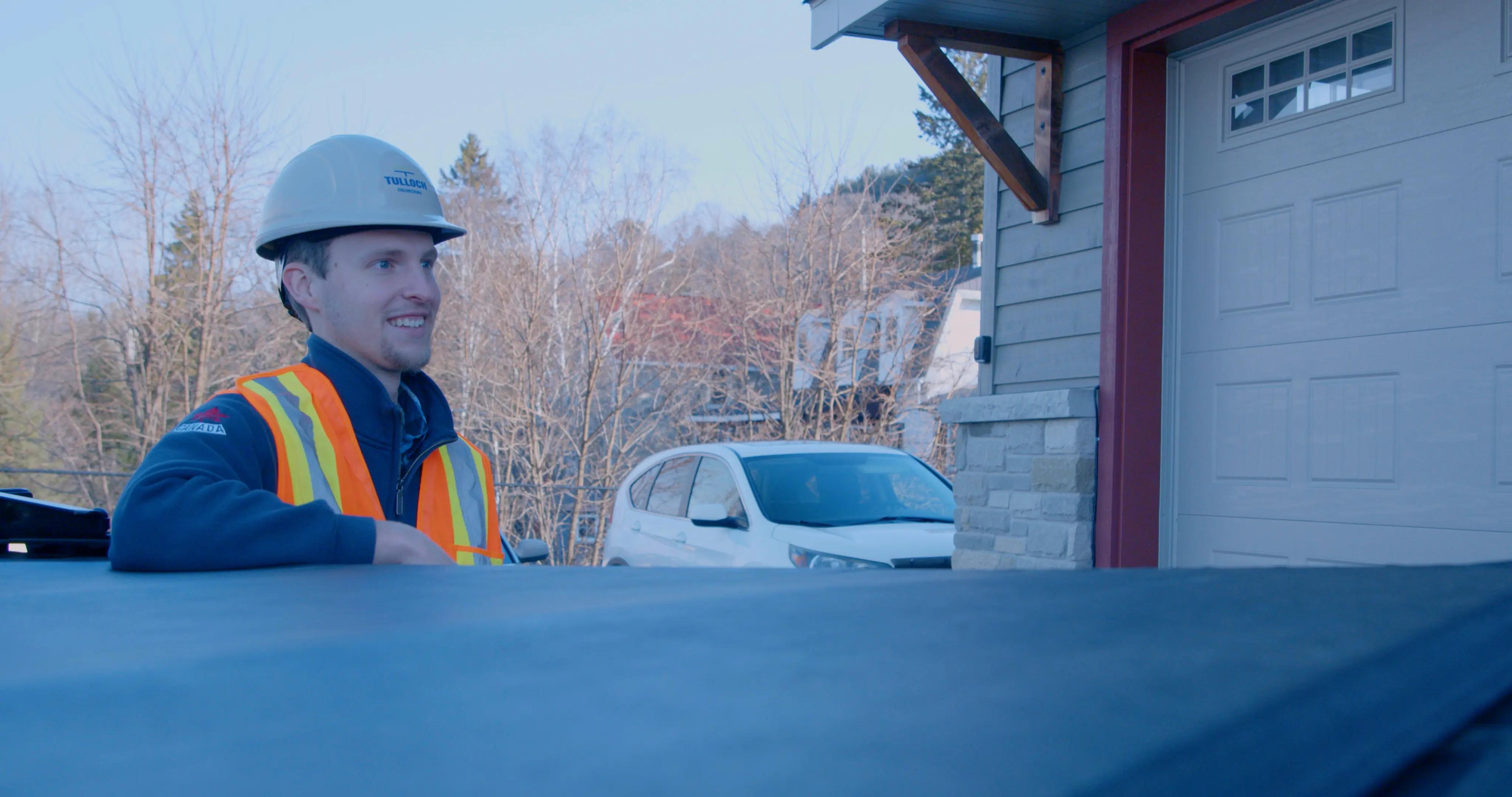TULLOCH field technician beside a company truck at a project site.