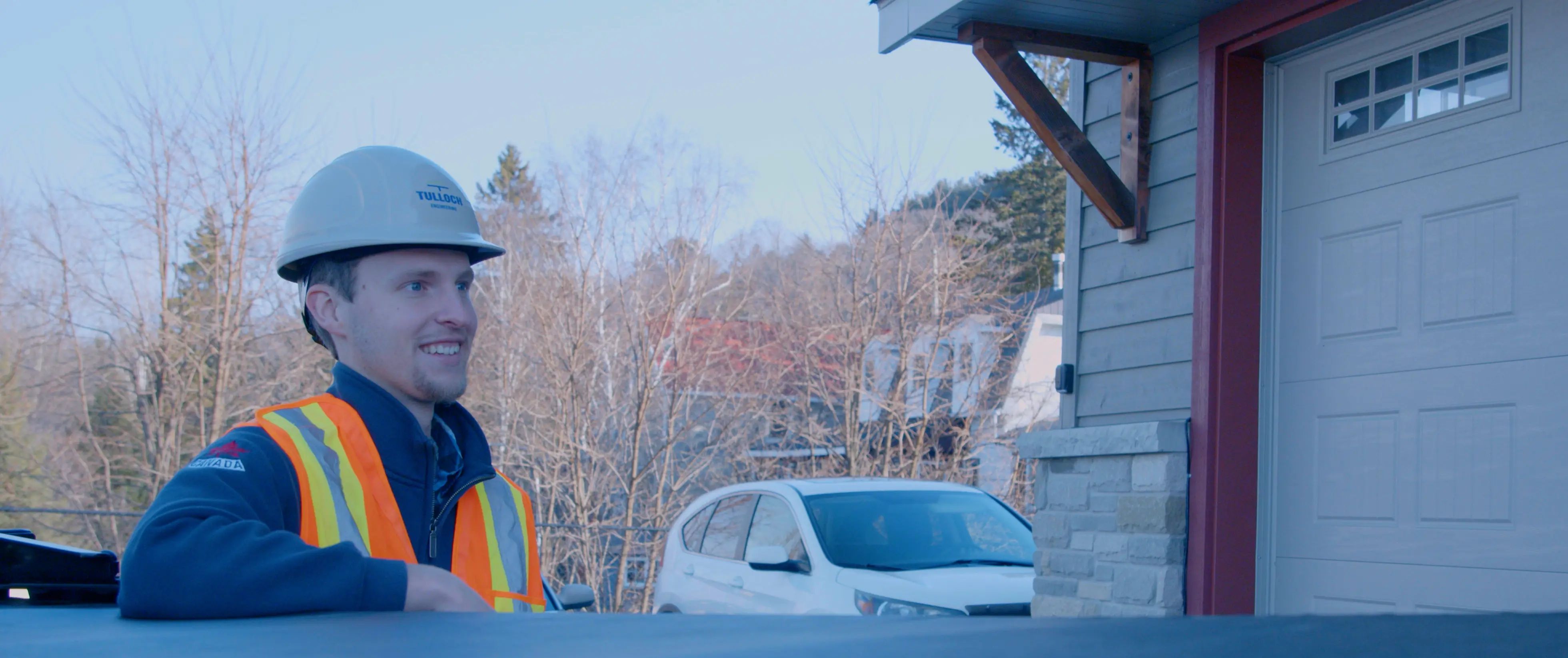 TULLOCH field technician beside a company truck at a project site.