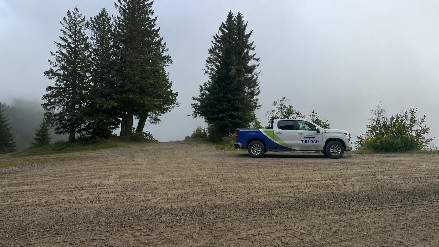 TULLOCH company truck parked at a remote field site overlooking water.