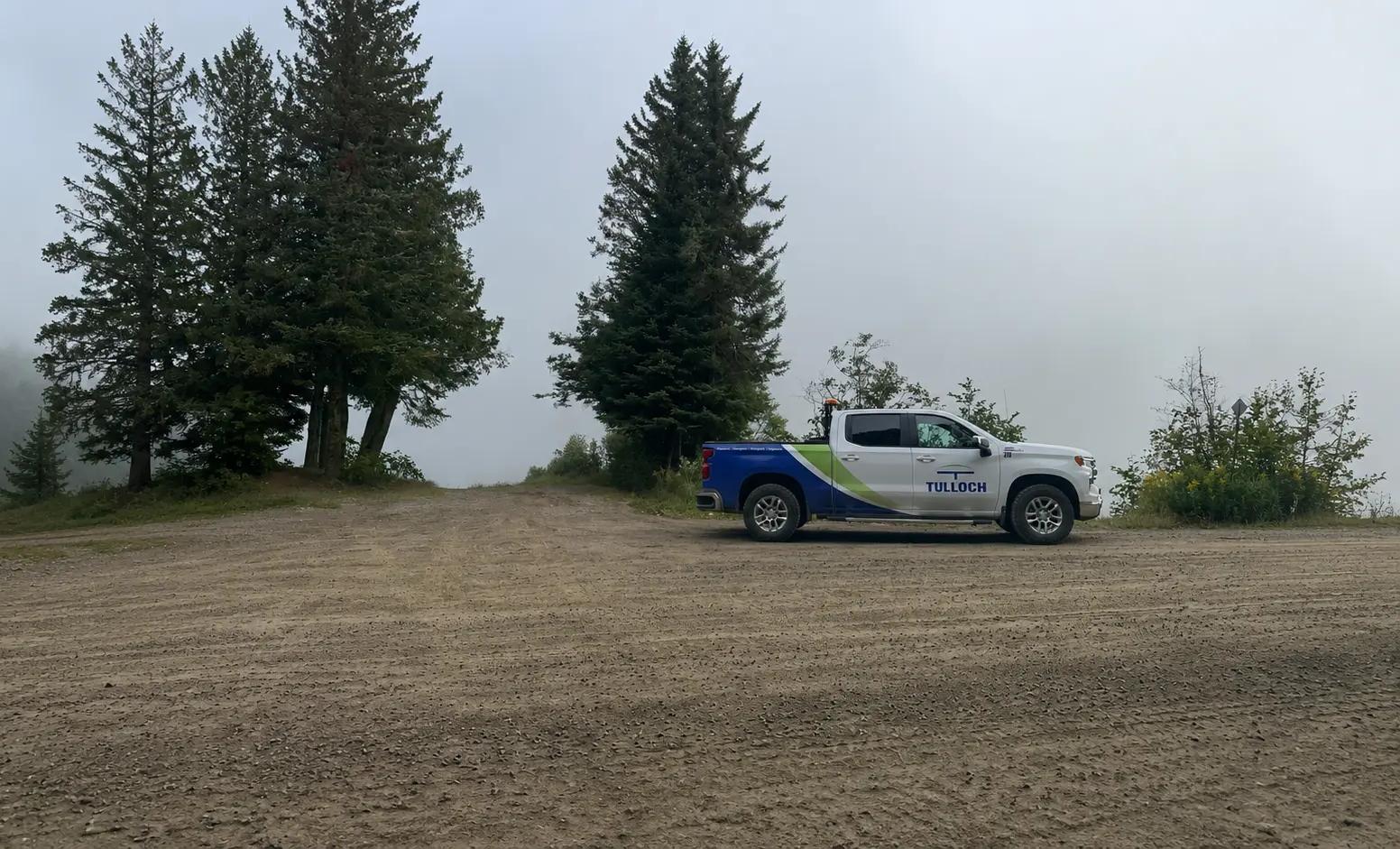 TULLOCH company truck parked at a remote field site overlooking water.