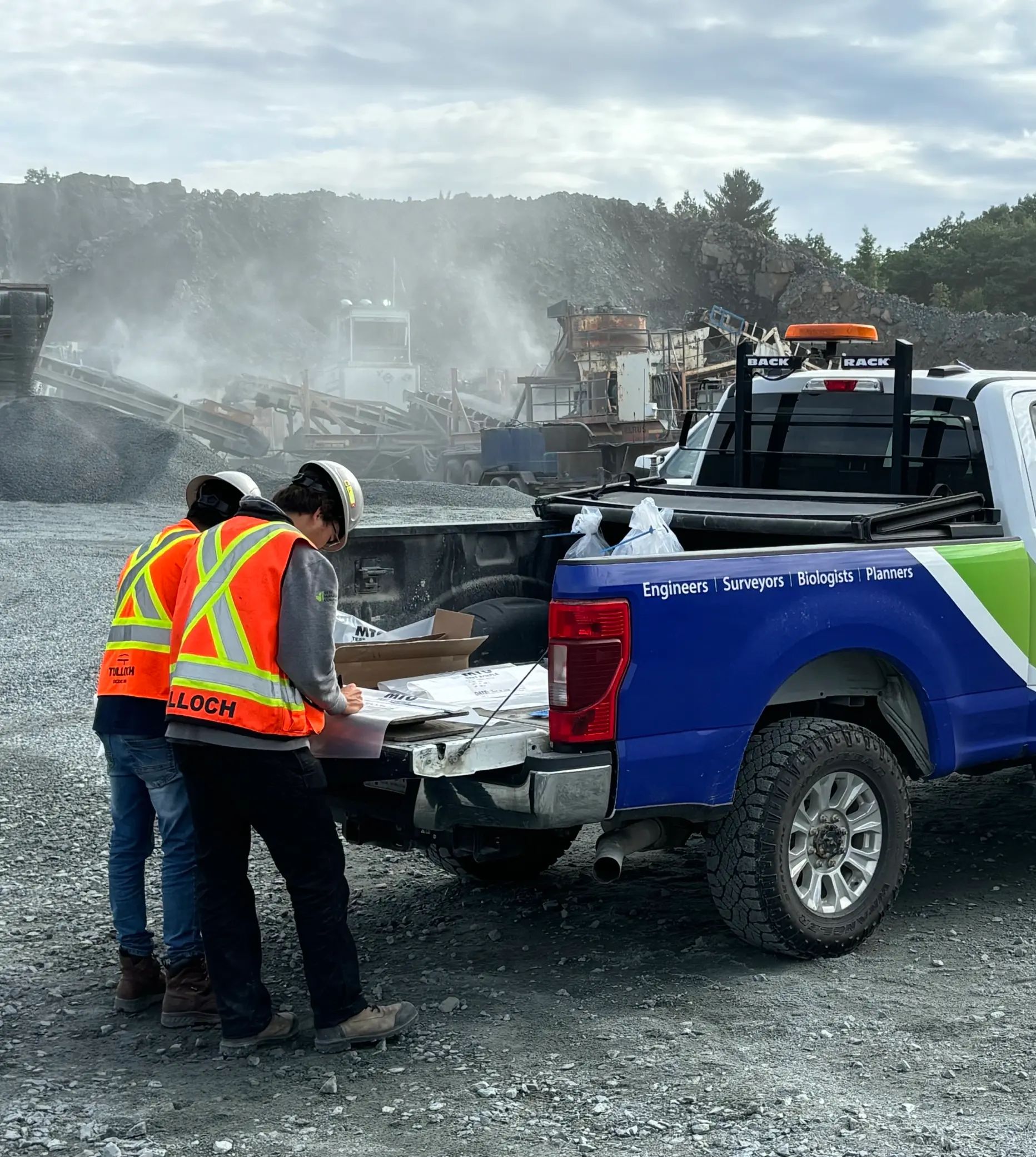TULLOCH field technicians preparing equipment at the tailgate of a company truck.