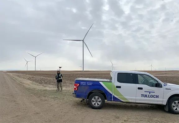 TULLOCH surveyor working beside a company truck at a wind farm.