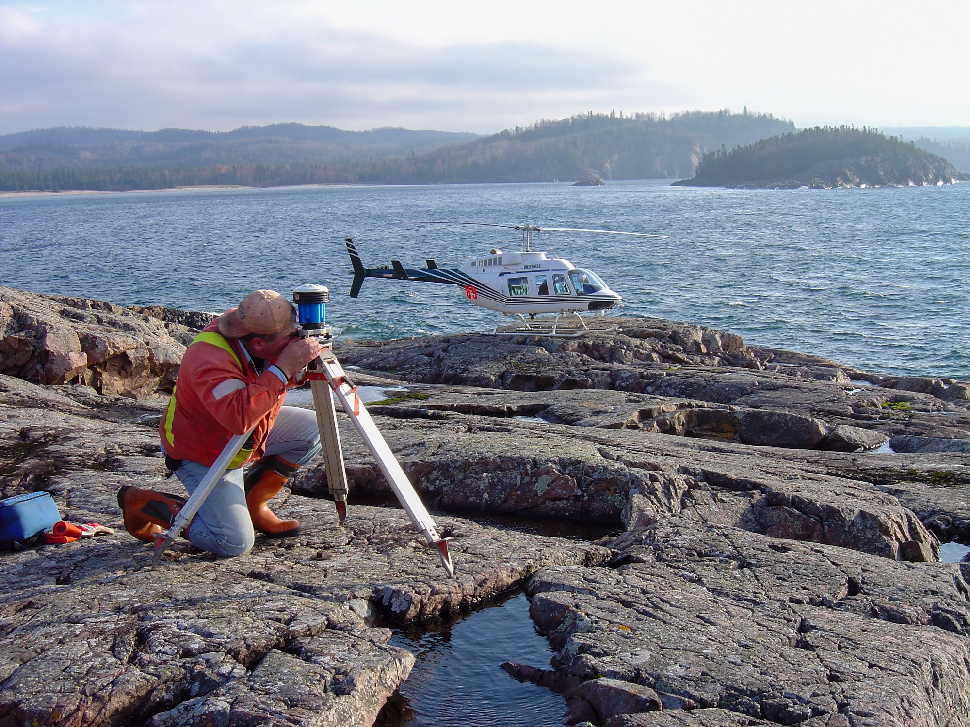 TULLOCH surveyor collecting field measurements along a rocky shoreline.