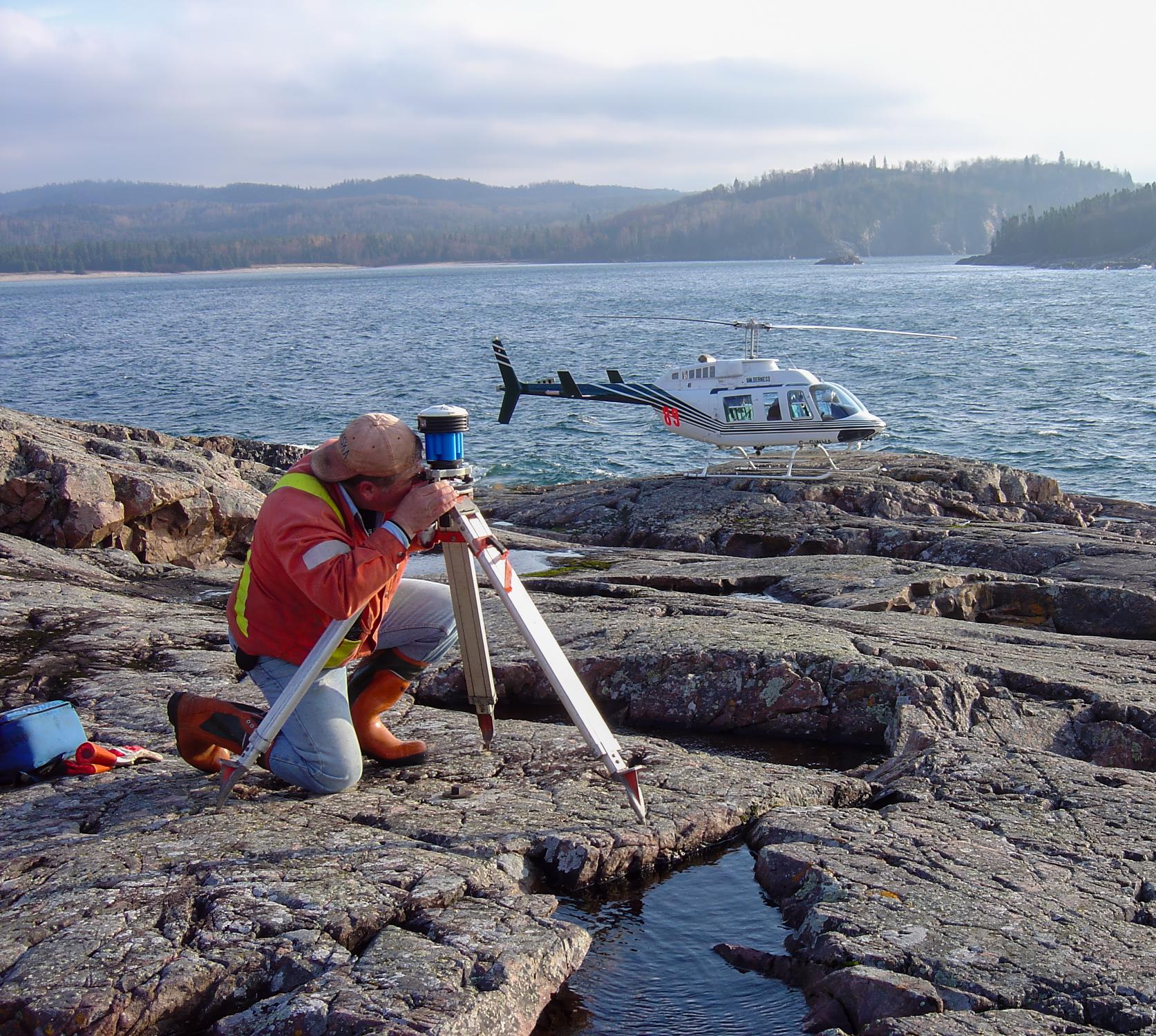 TULLOCH surveyor collecting field measurements along a rocky shoreline.