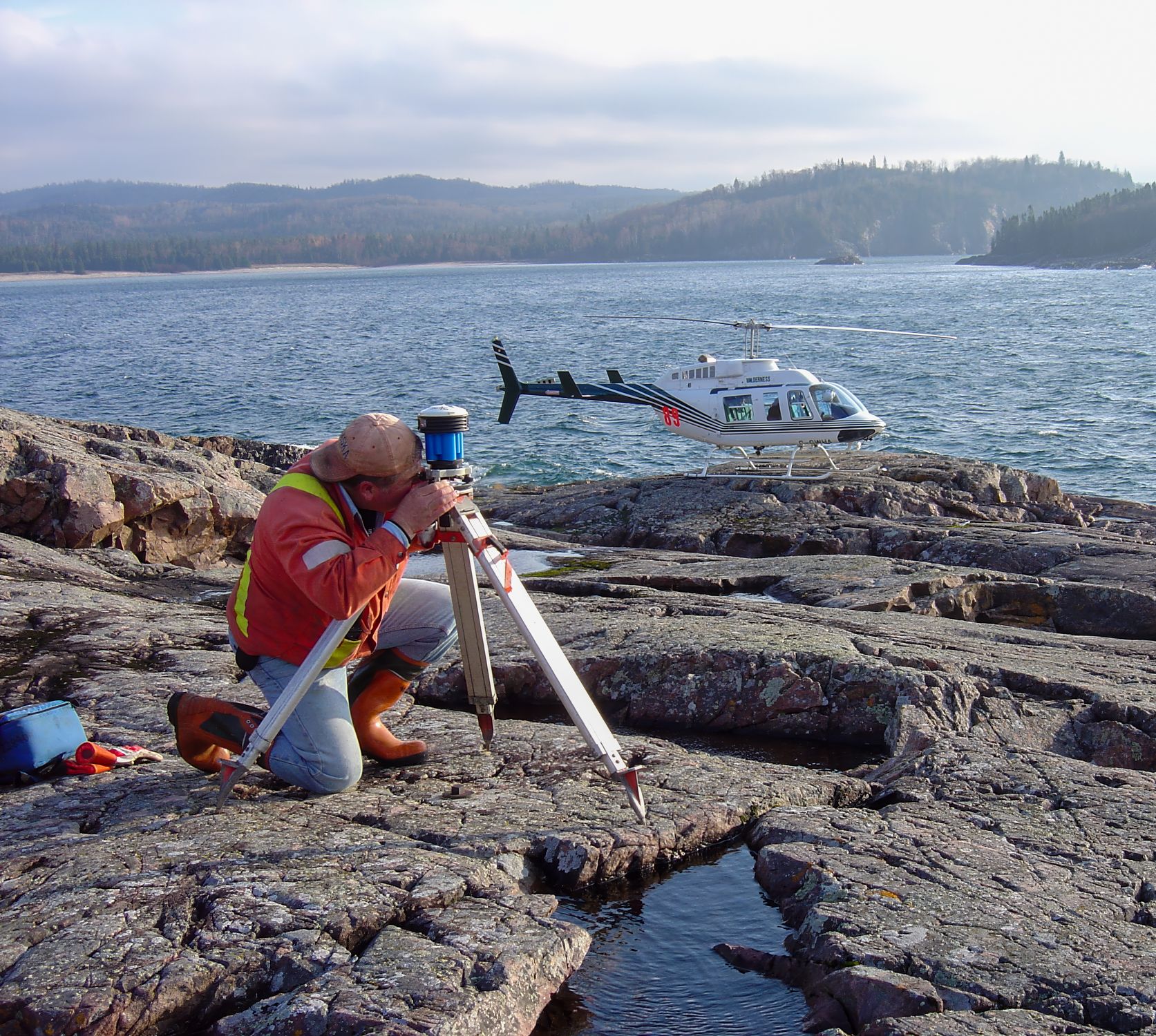 TULLOCH surveyor collecting field measurements along a rocky shoreline.