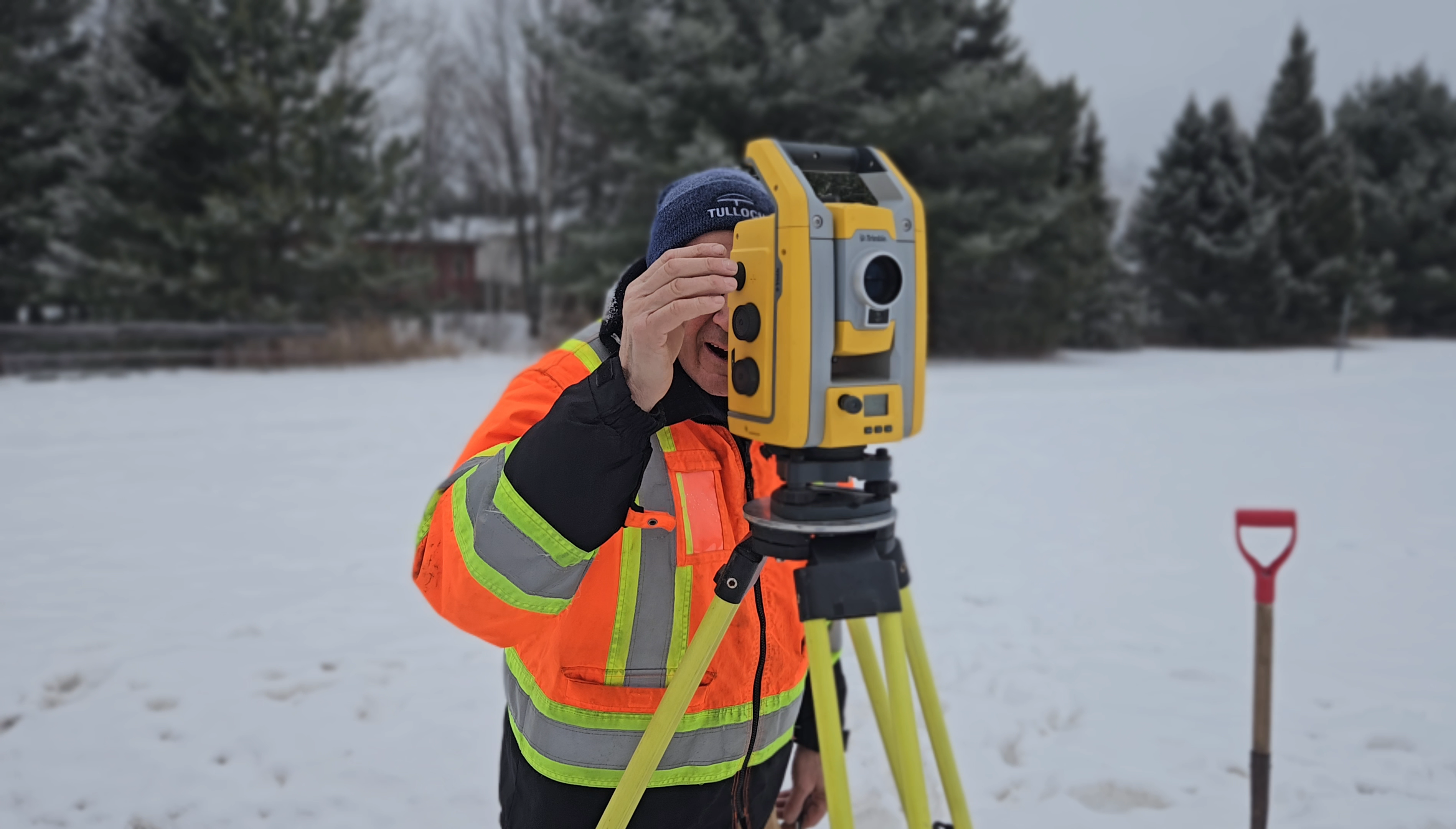 TULLOCH surveyor looking through a total station during winter fieldwork.