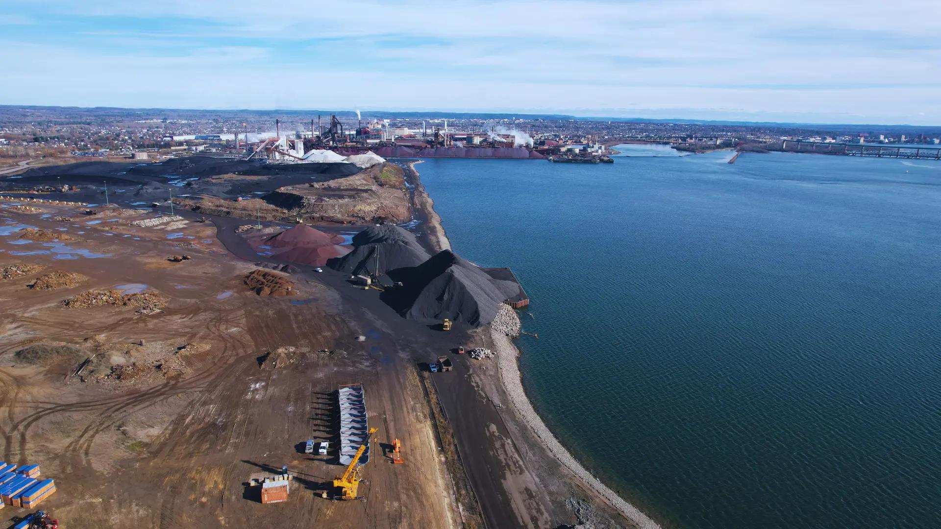 Aerial view of shoreline construction and site works beside a large waterbody.