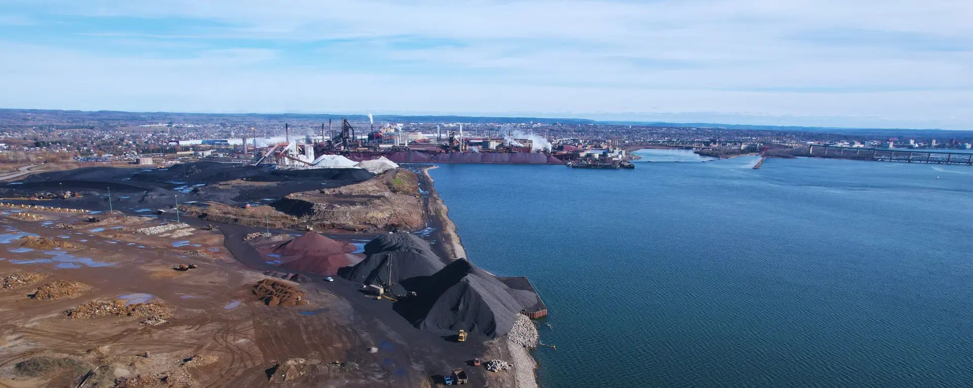 Aerial view of shoreline construction and site works beside a large waterbody.