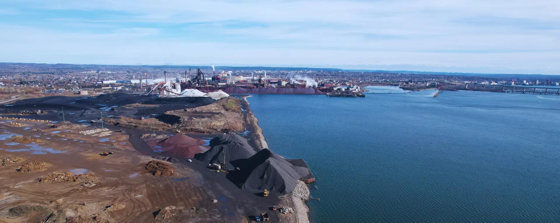 Aerial view of shoreline construction and site works beside a large waterbody.