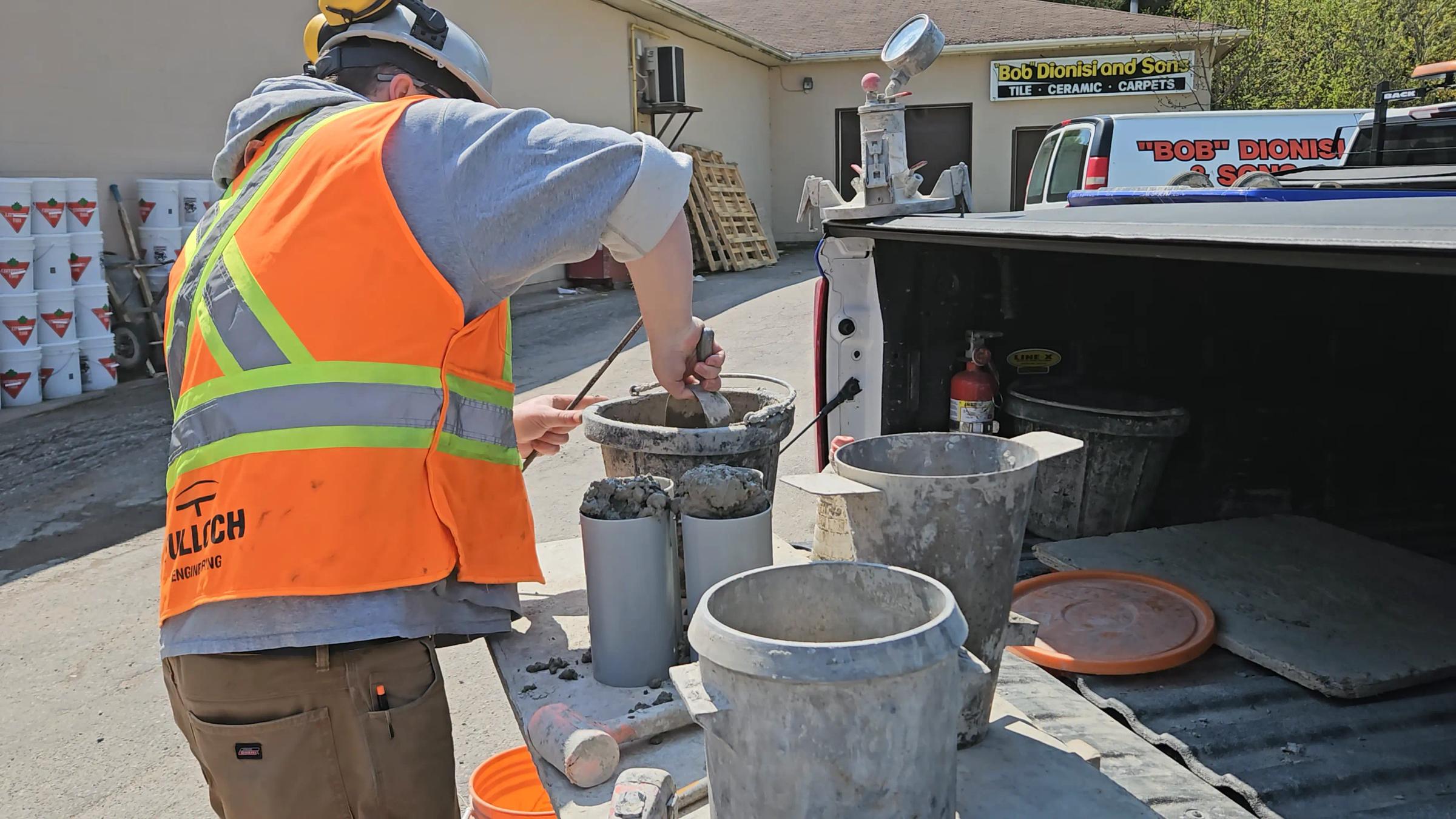 TULLOCH materials testing technician preparing concrete samples at a field laboratory.