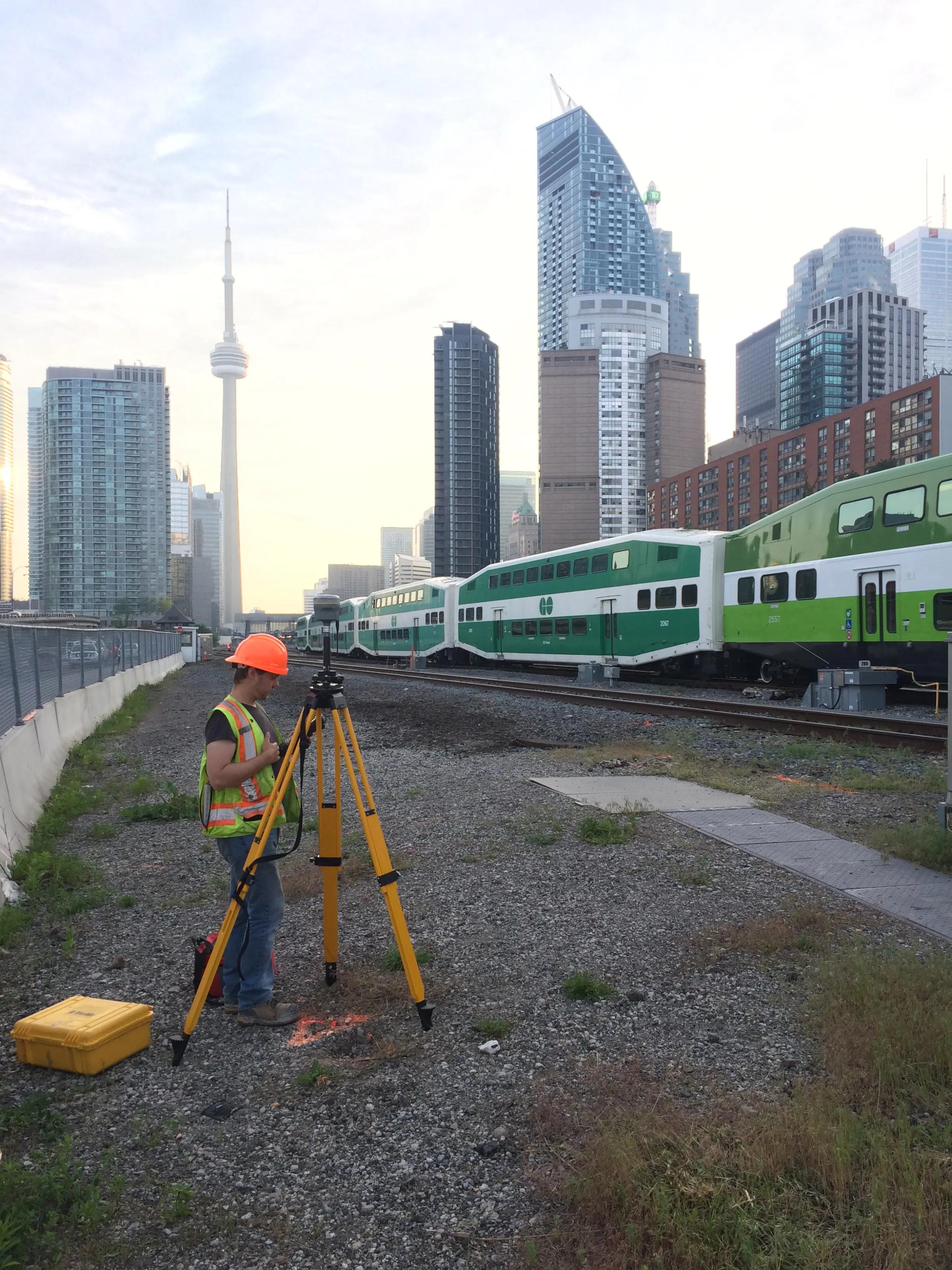 TULLOCH field technician operating survey equipment beside an active rail corridor.
