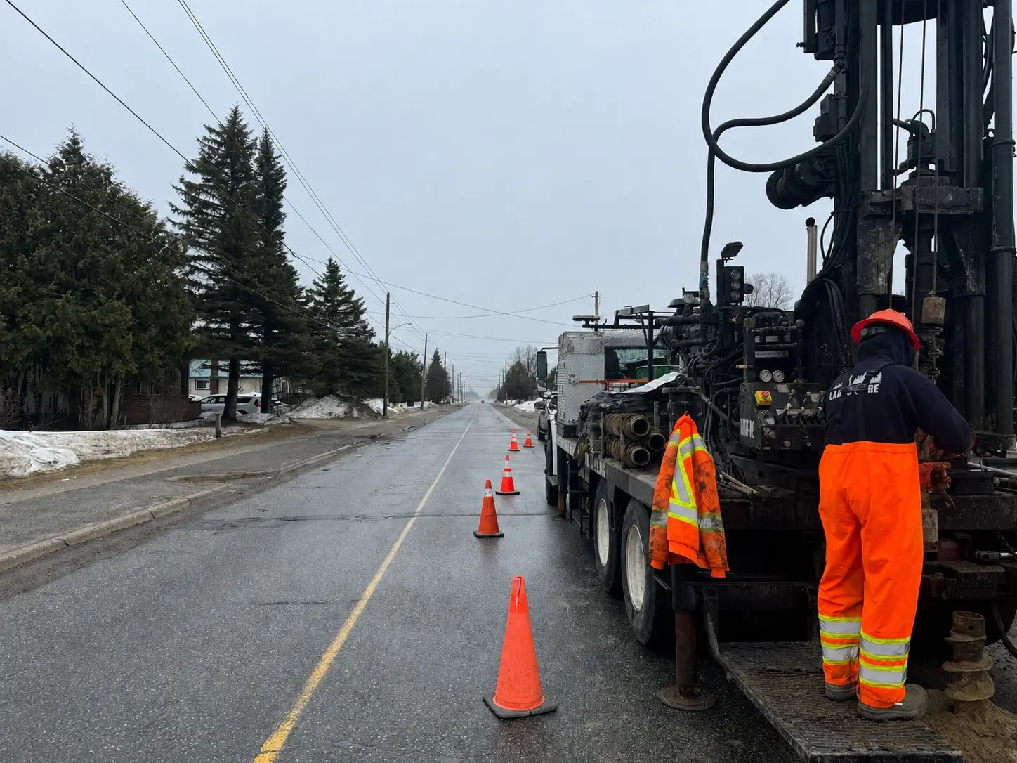 Geotechnical drilling crew working beside an active municipal roadway.