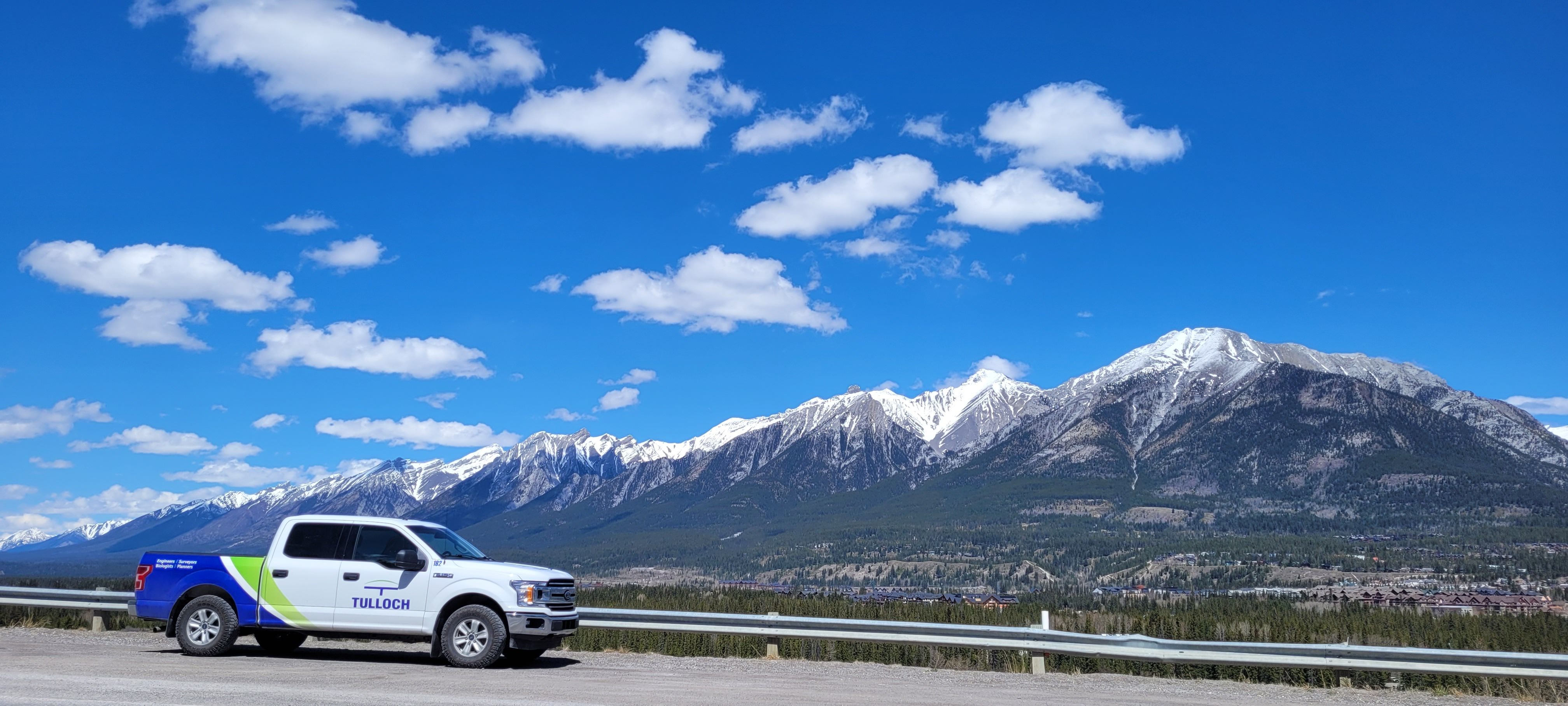 TULLOCH company truck parked beside a mountain corridor.