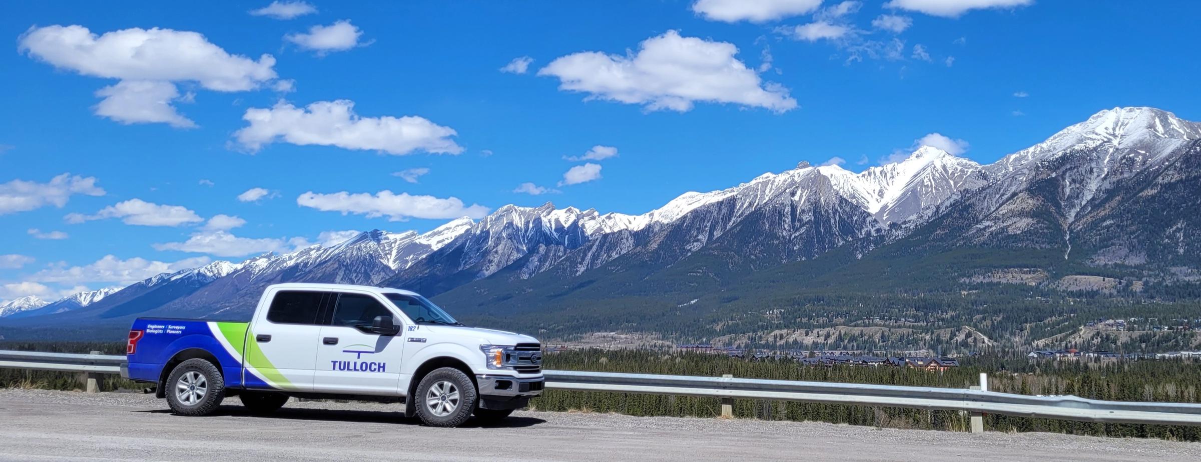 TULLOCH company truck parked beside a mountain corridor.