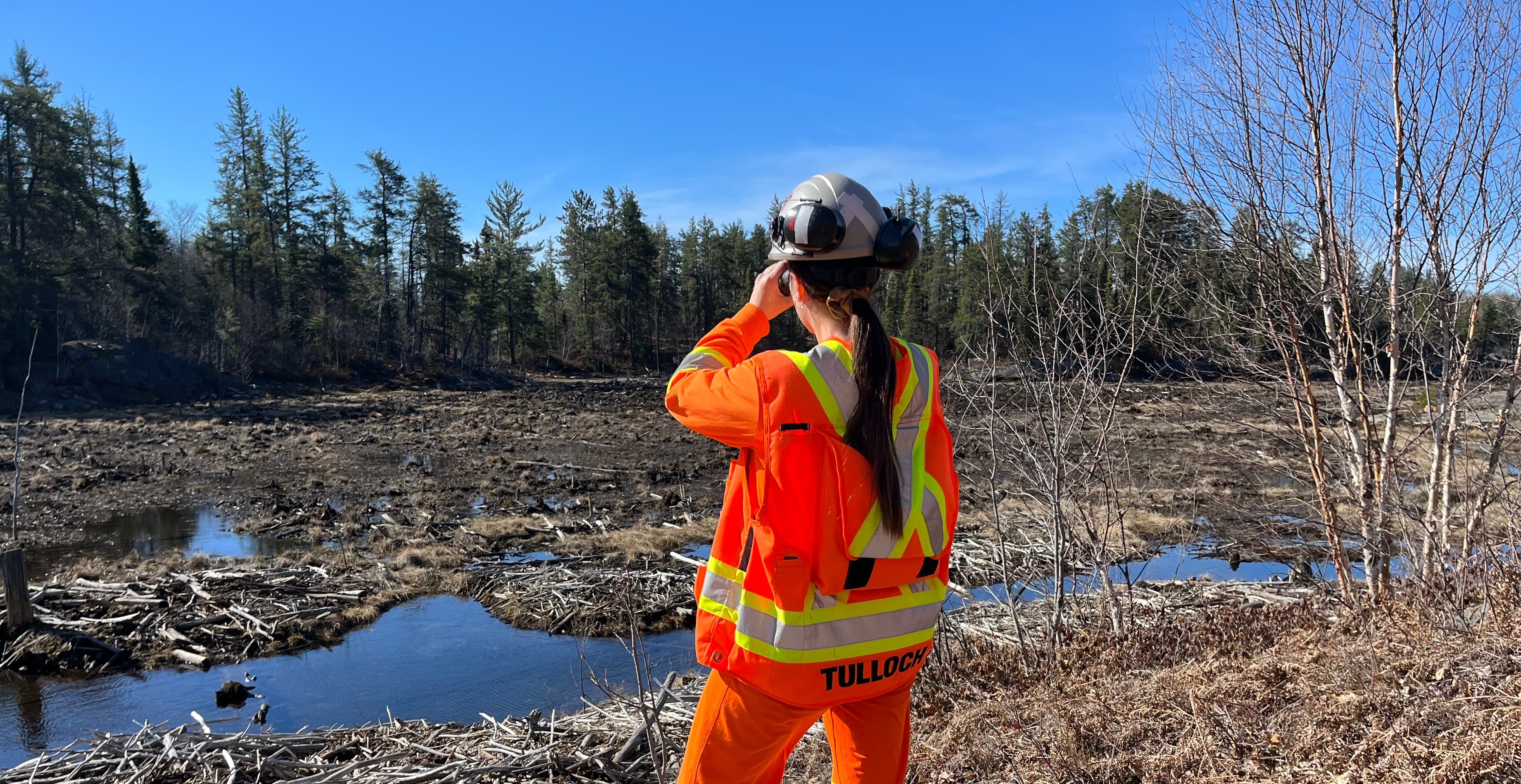 TULLOCH field technician assessing a shoreline rehabilitation area near a waterbody.