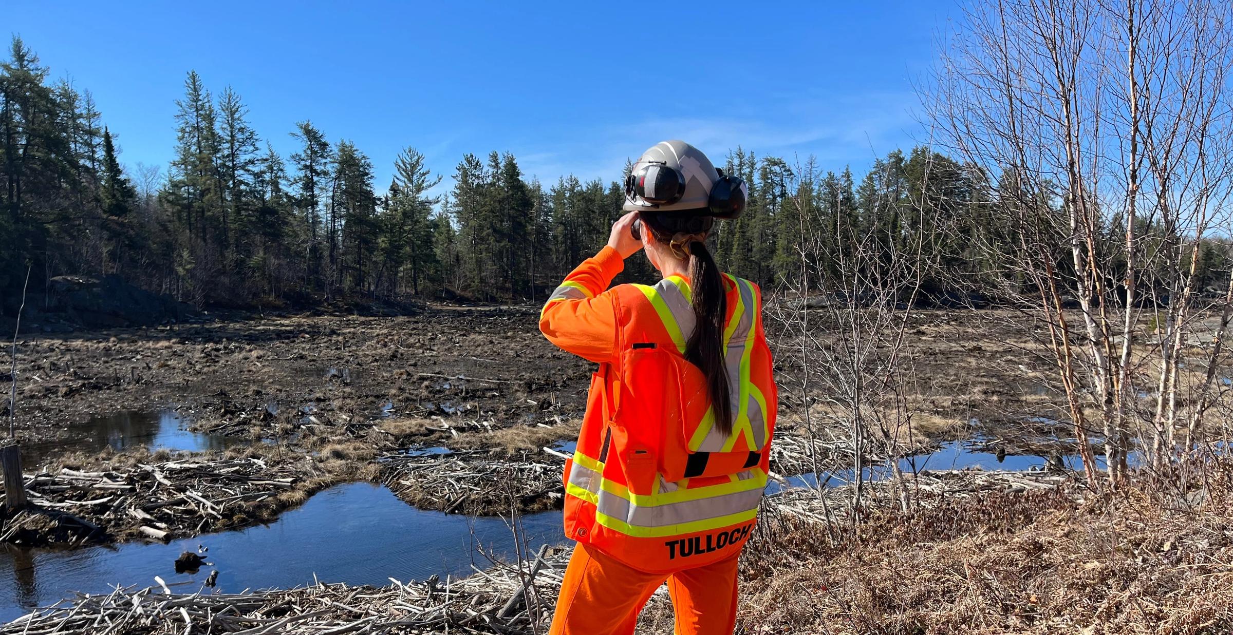 TULLOCH field technician assessing a shoreline rehabilitation area near a waterbody.