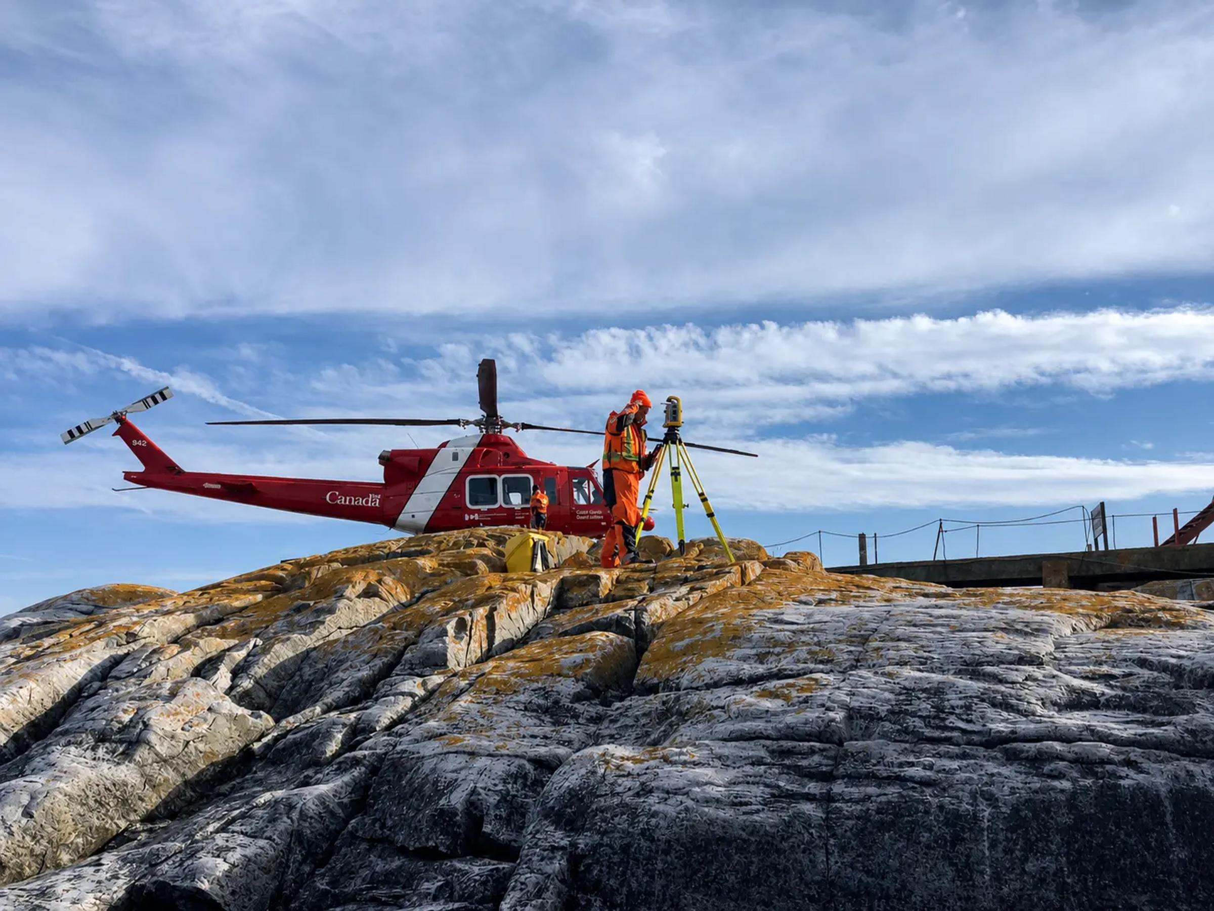 Helicopter positioned on a remote rocky site for field mobilization.