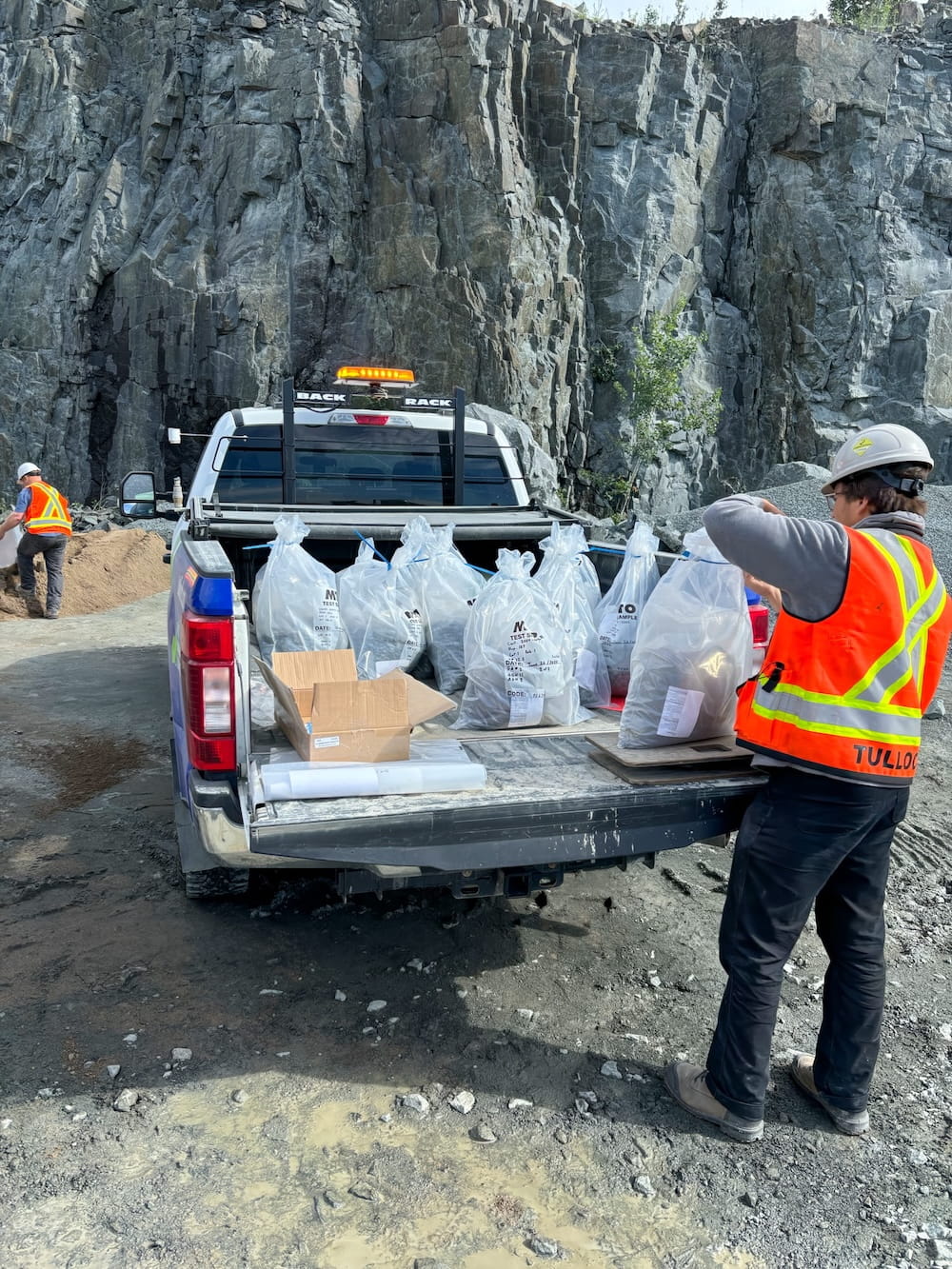 TULLOCH field technician handling samples or testing equipment at a rocky project site.