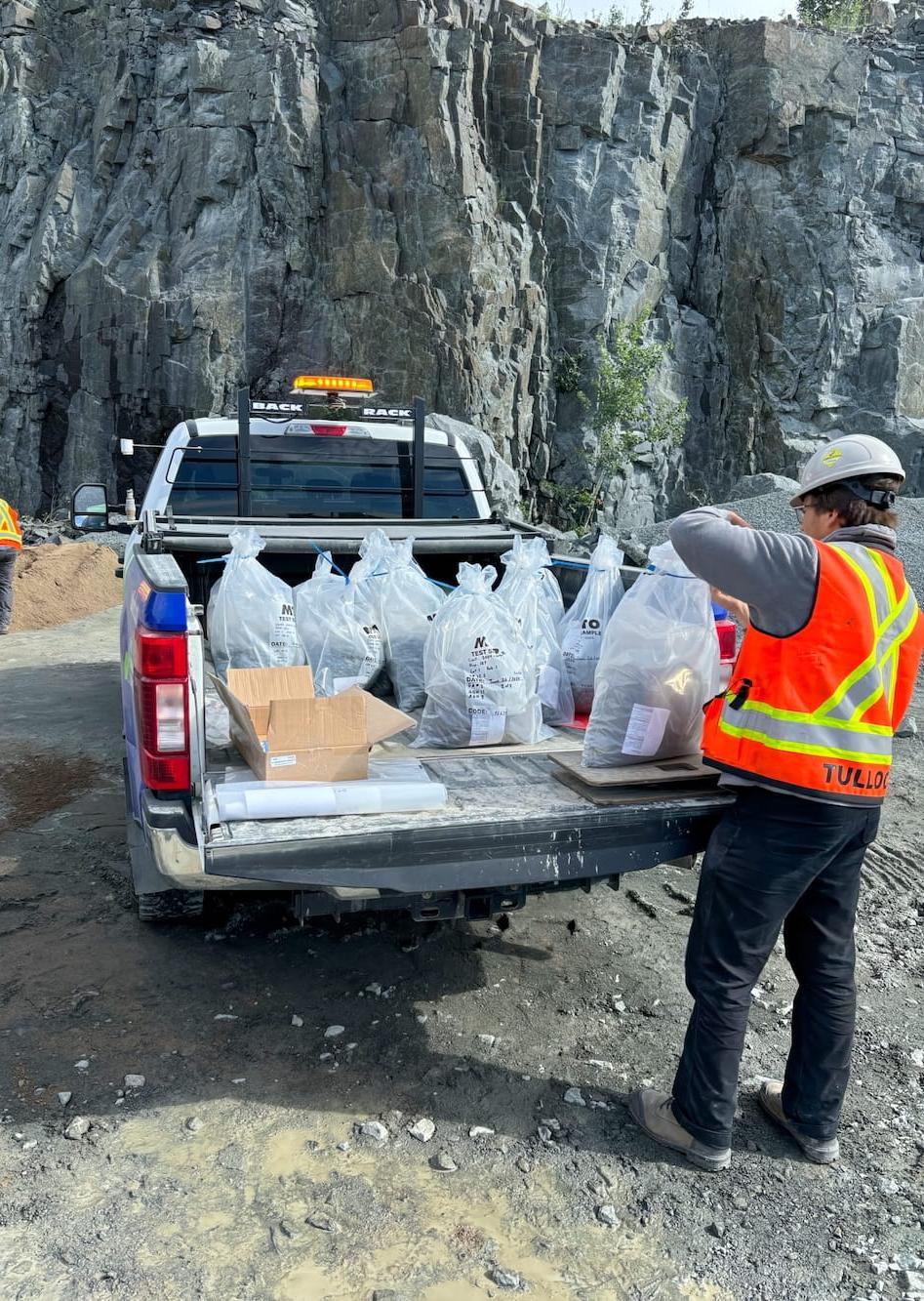 TULLOCH field technician handling samples or testing equipment at a rocky project site.
