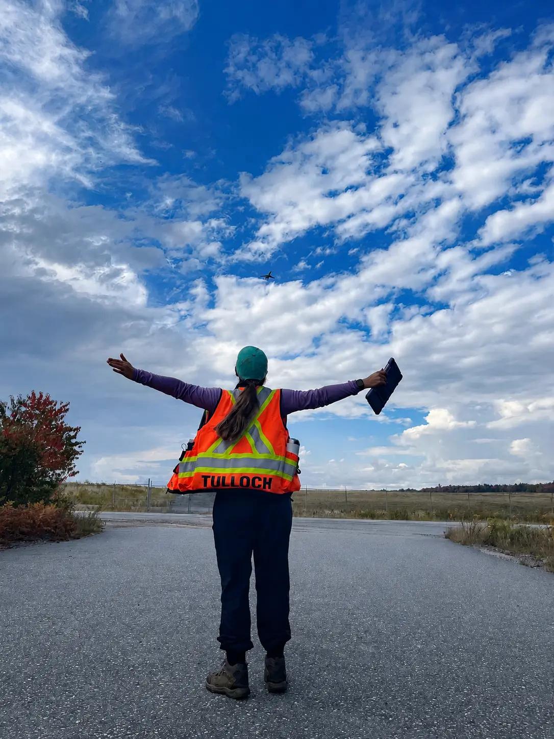 TULLOCH field technician standing on a remote project road under a wide sky.