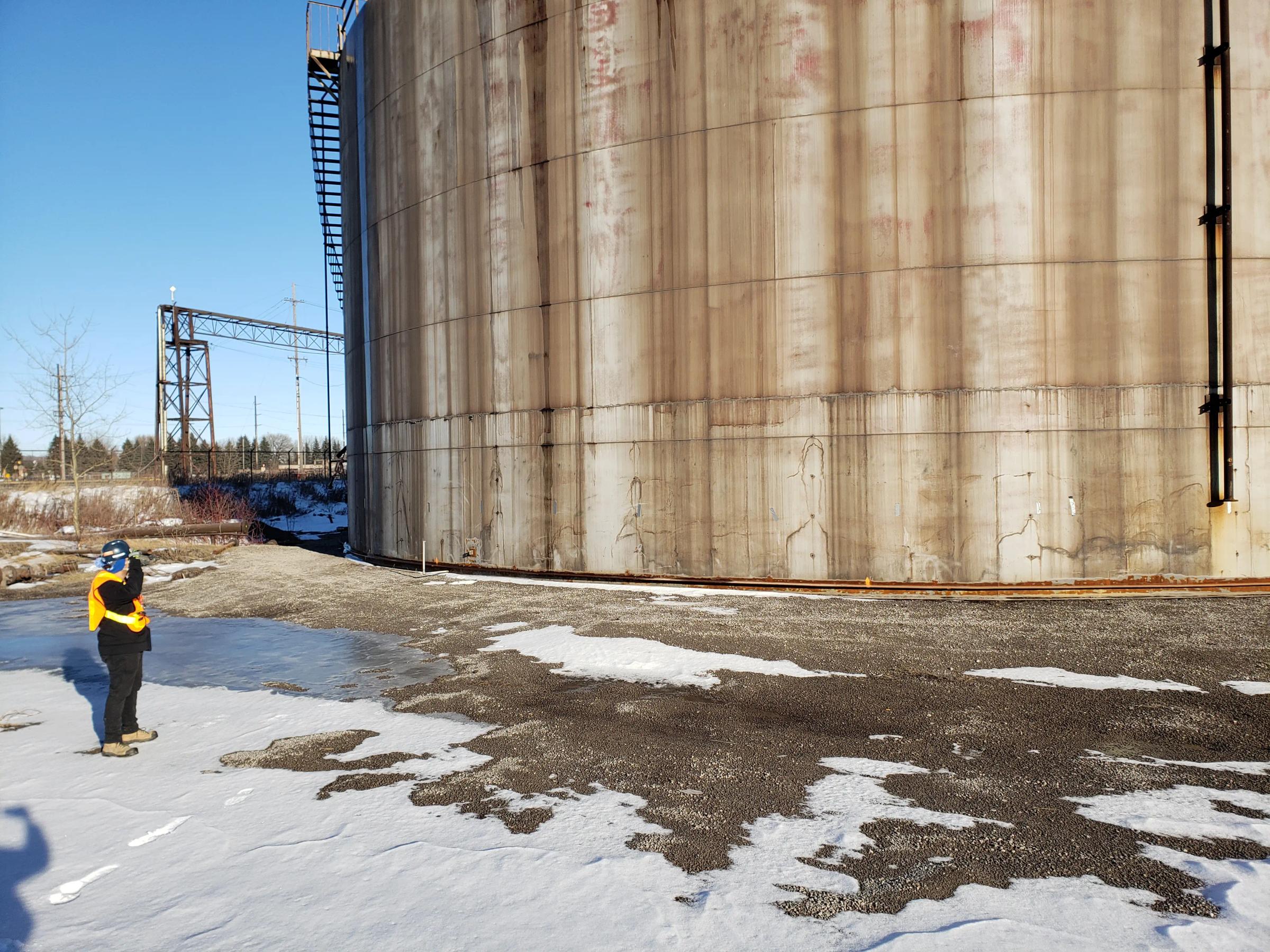 Field inspection beside a large industrial storage silo.