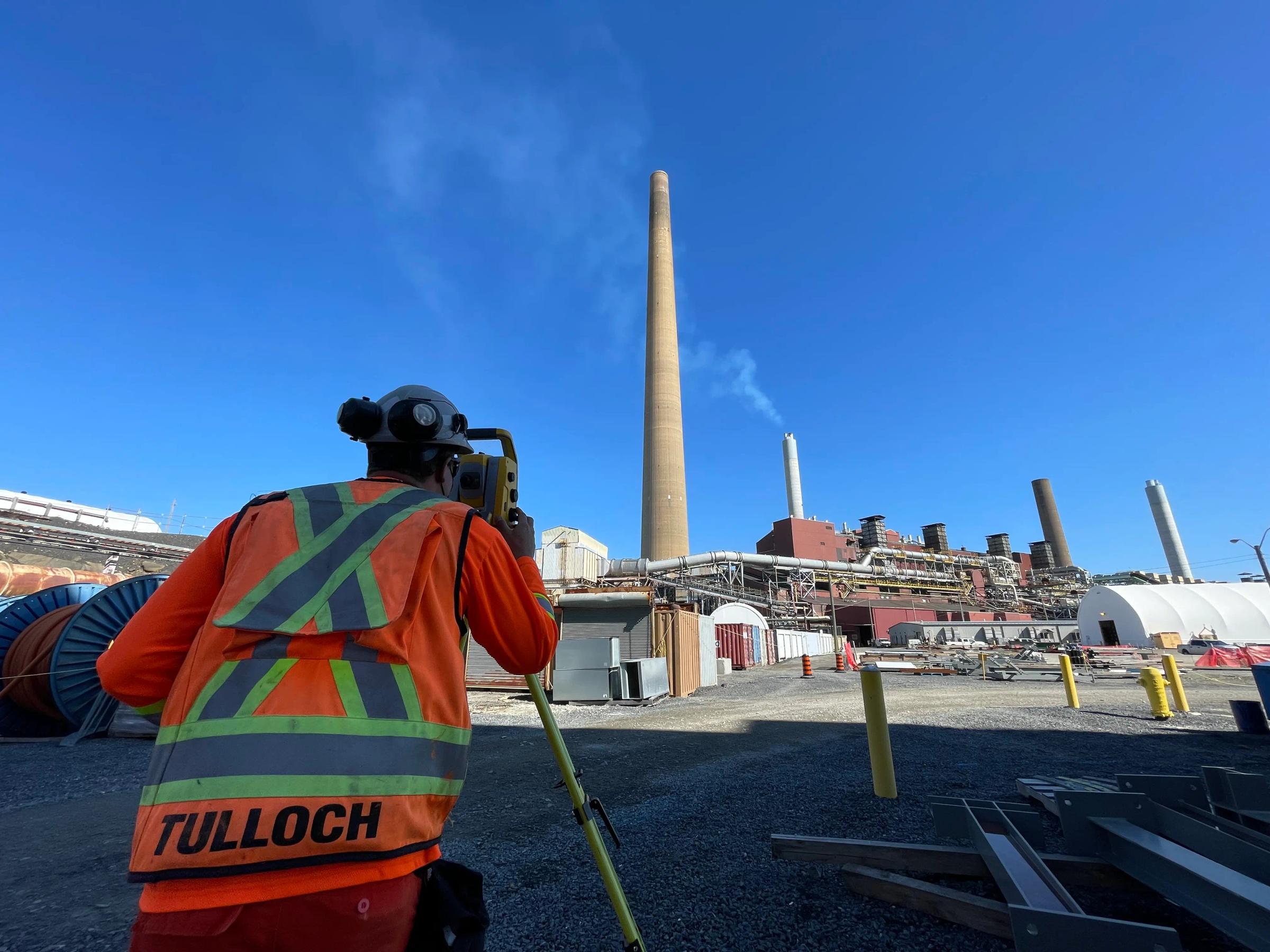 TULLOCH surveyor operating a total station near an industrial facility.