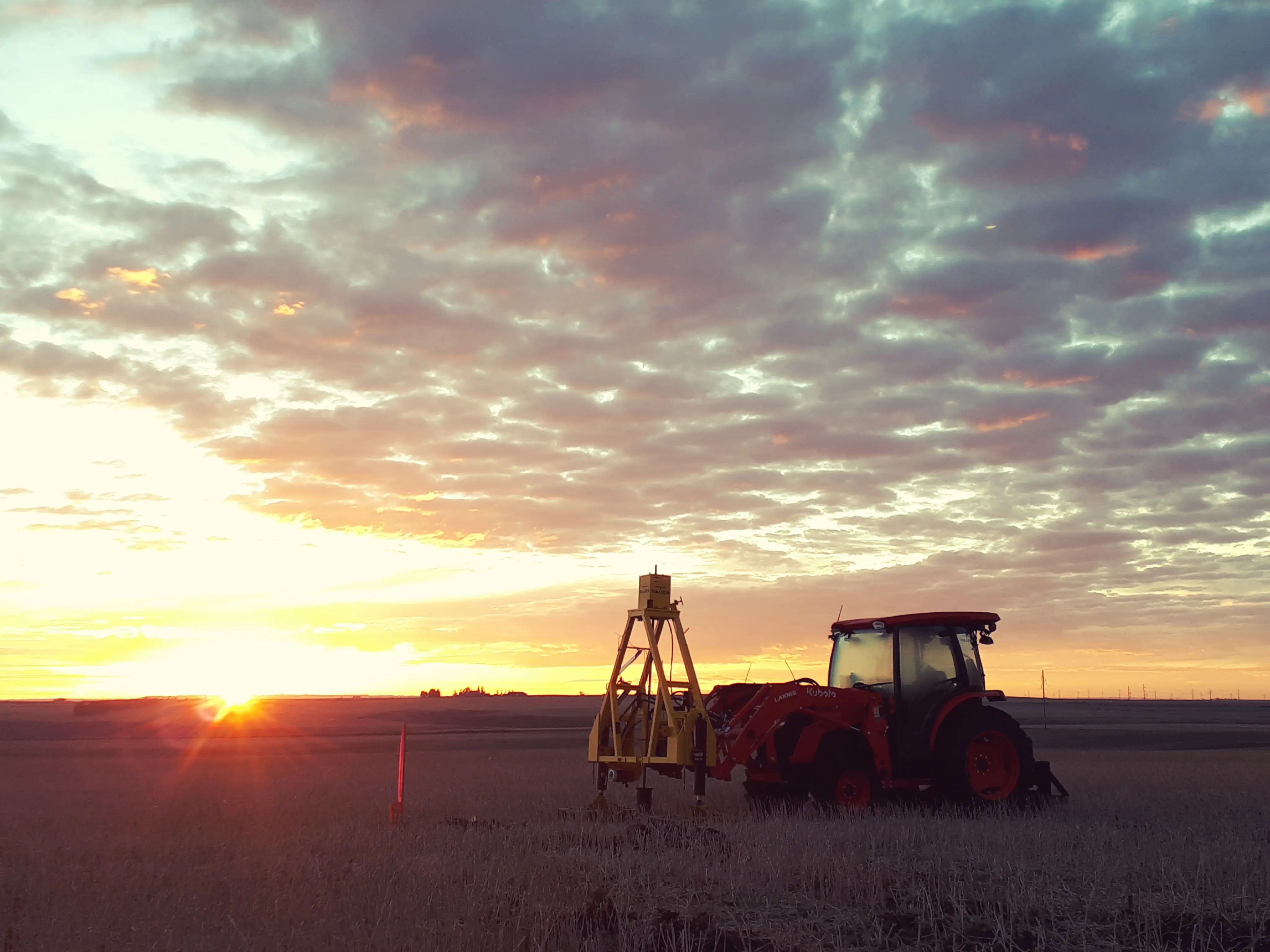 Solar foundation testing equipment operating at a project site near sunset.