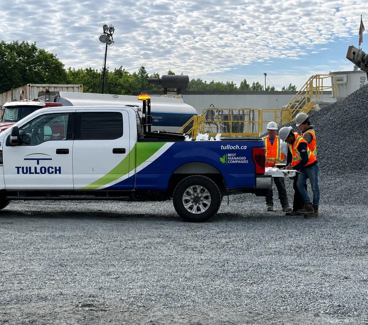 TULLOCH field crew reviewing project drawings beside a company truck.
