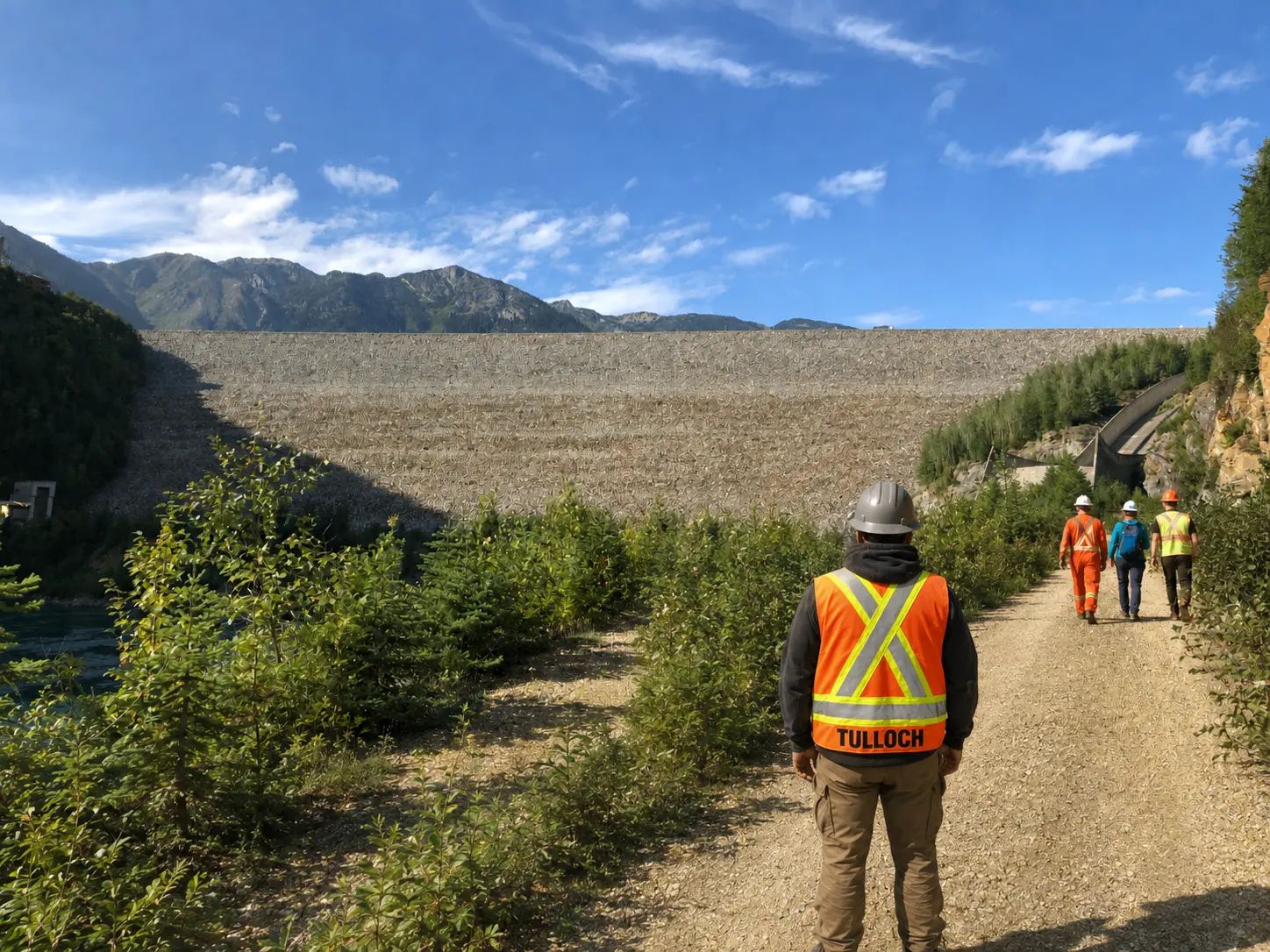 TULLOCH field technician walking along a dam access road.