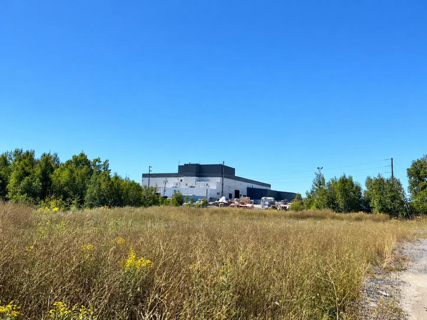 Grassy industrial site area included in a PFAS soil investigation near North Bay.