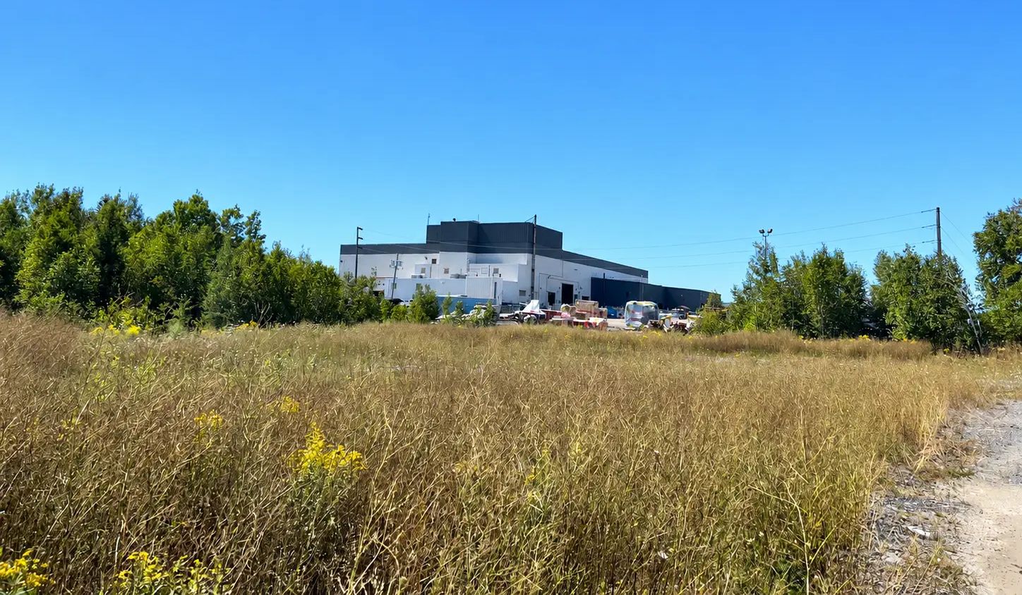 Grassy industrial site area included in a PFAS soil investigation near North Bay.
