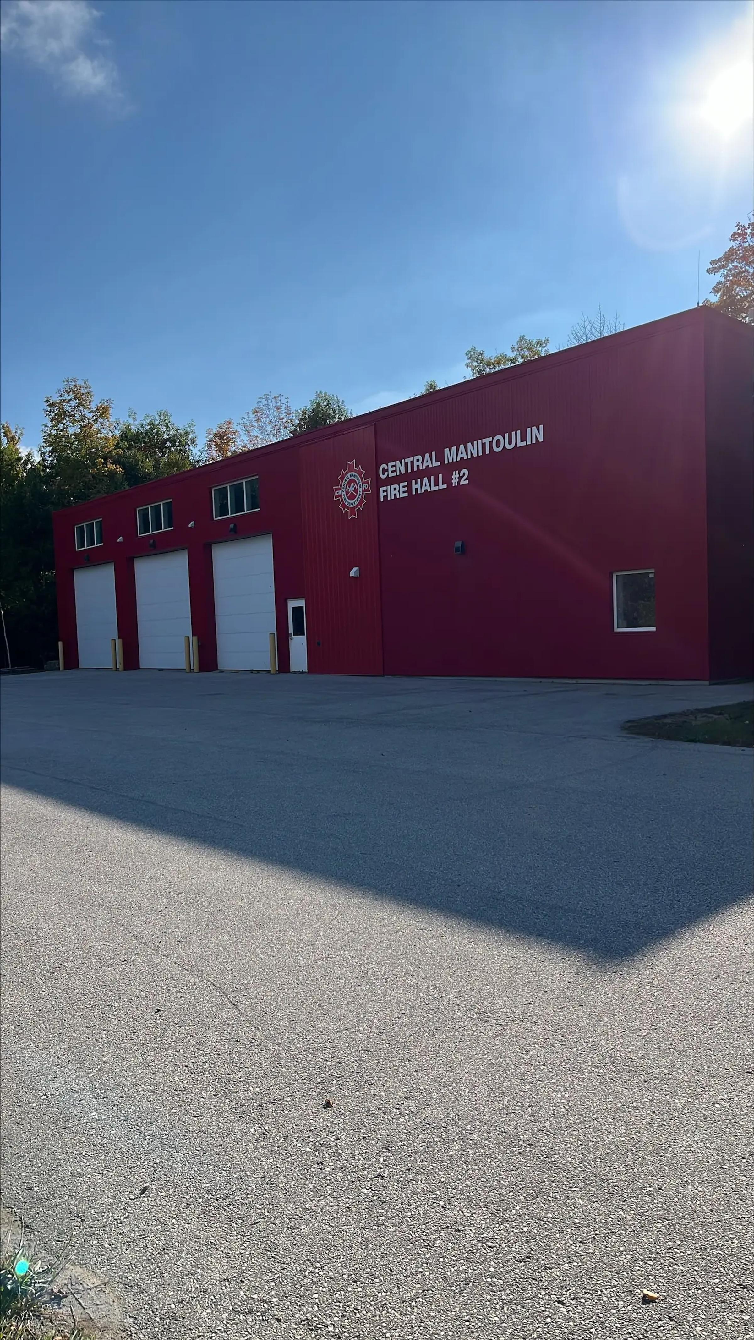 Exterior view of a fire hall building and paved access area.