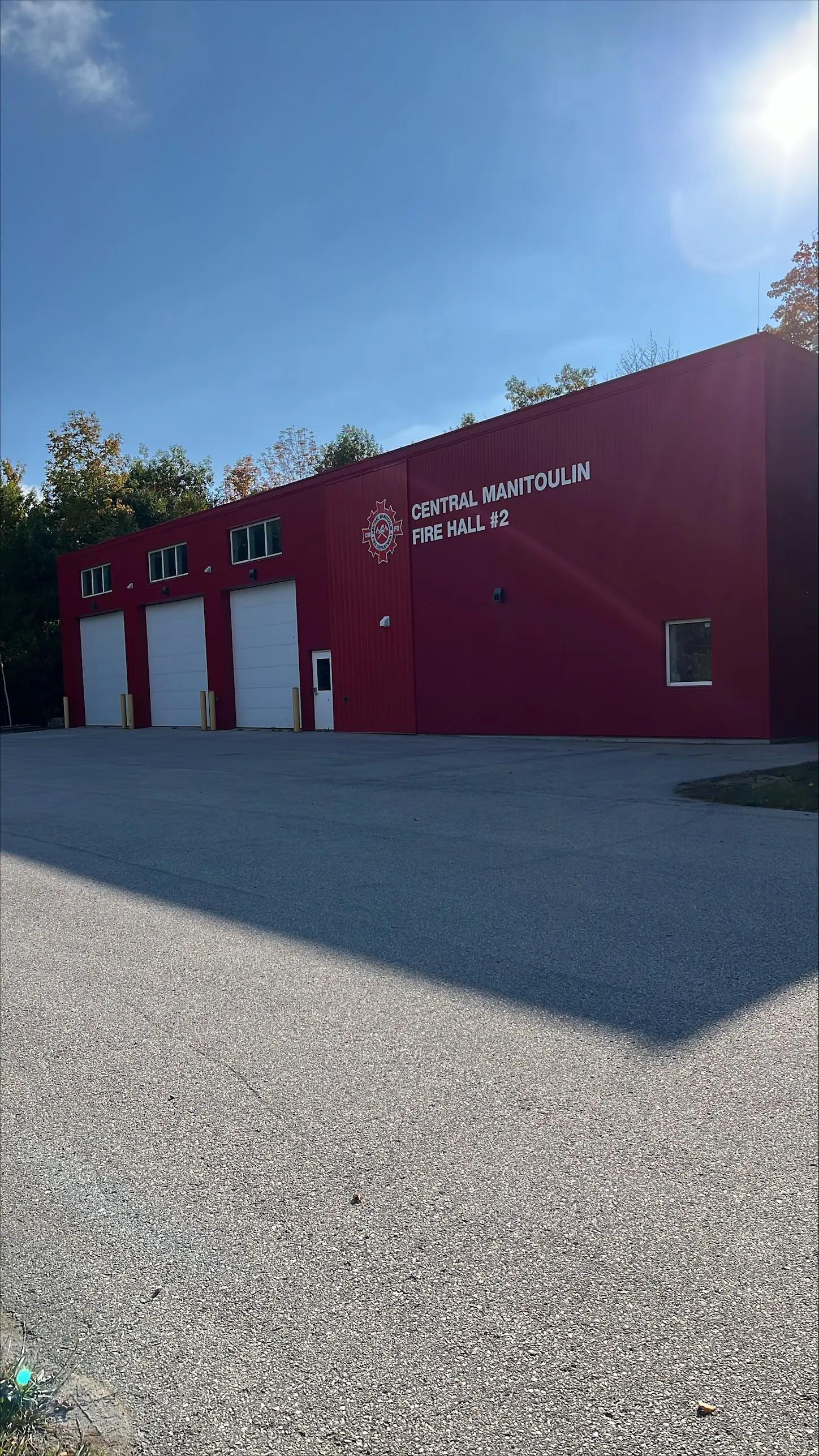 Exterior view of a fire hall building and paved access area.