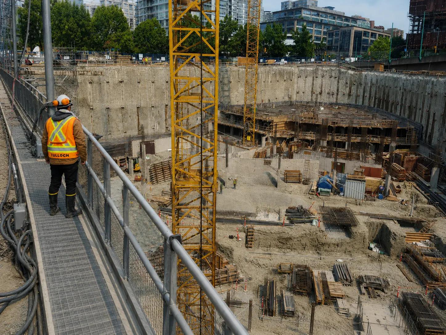 TULLOCH field technician observing a deep excavation at an active construction site.