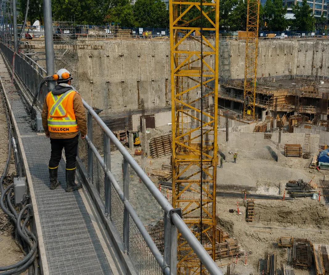 TULLOCH field technician observing a deep excavation at an active construction site.