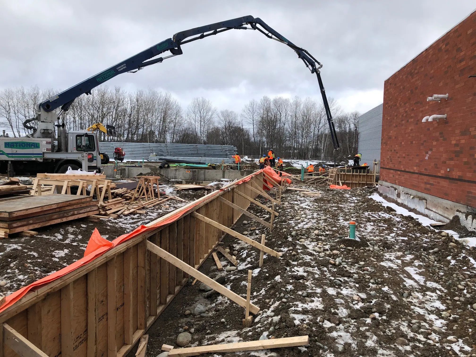 Concrete placement underway for a building foundation during winter construction.