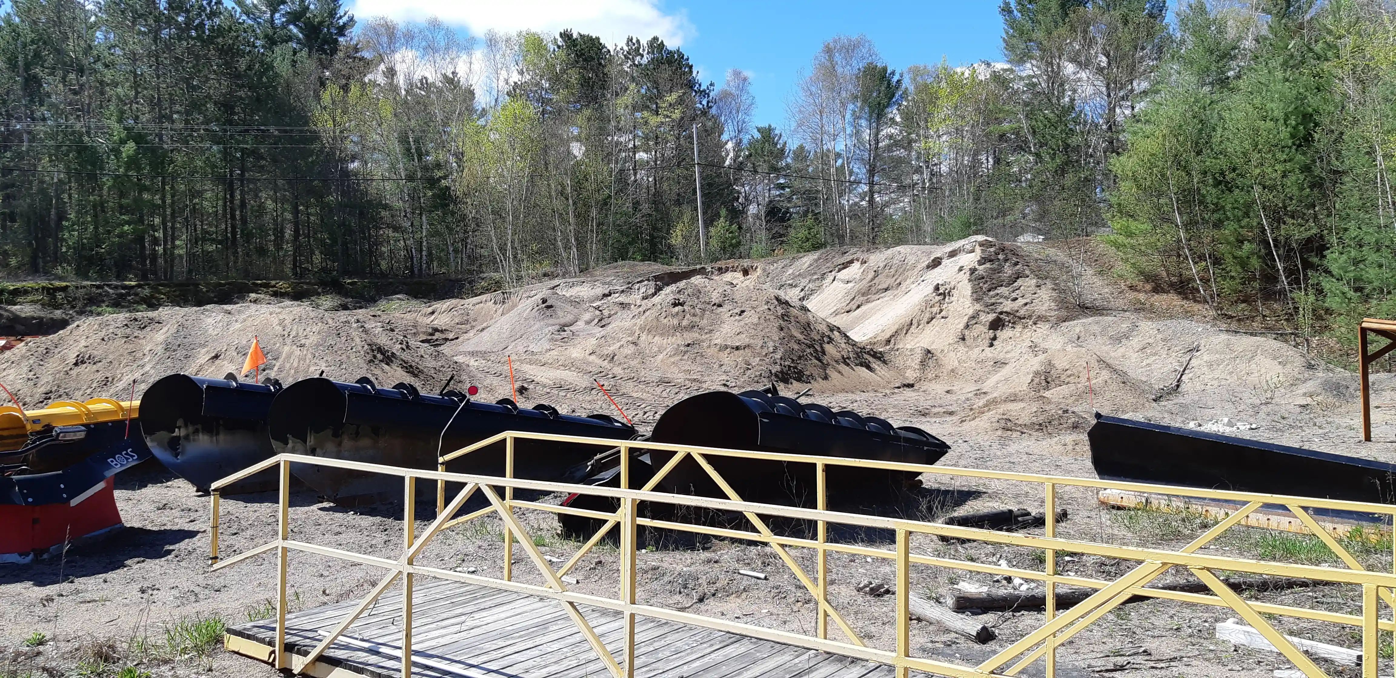 Construction earthworks and temporary access beside a wooded watercourse.