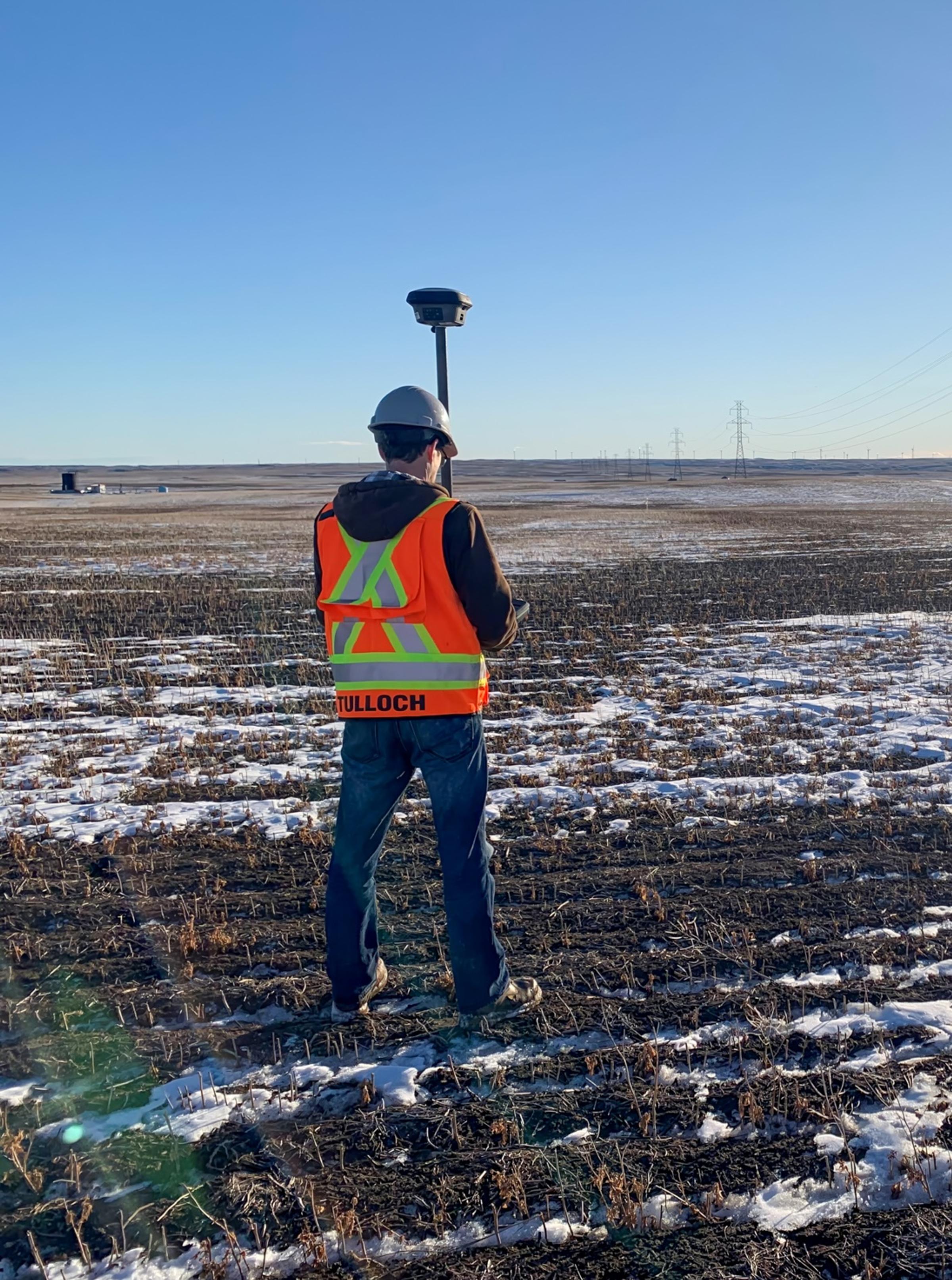 TULLOCH field surveyor collecting data across an open energy project site.