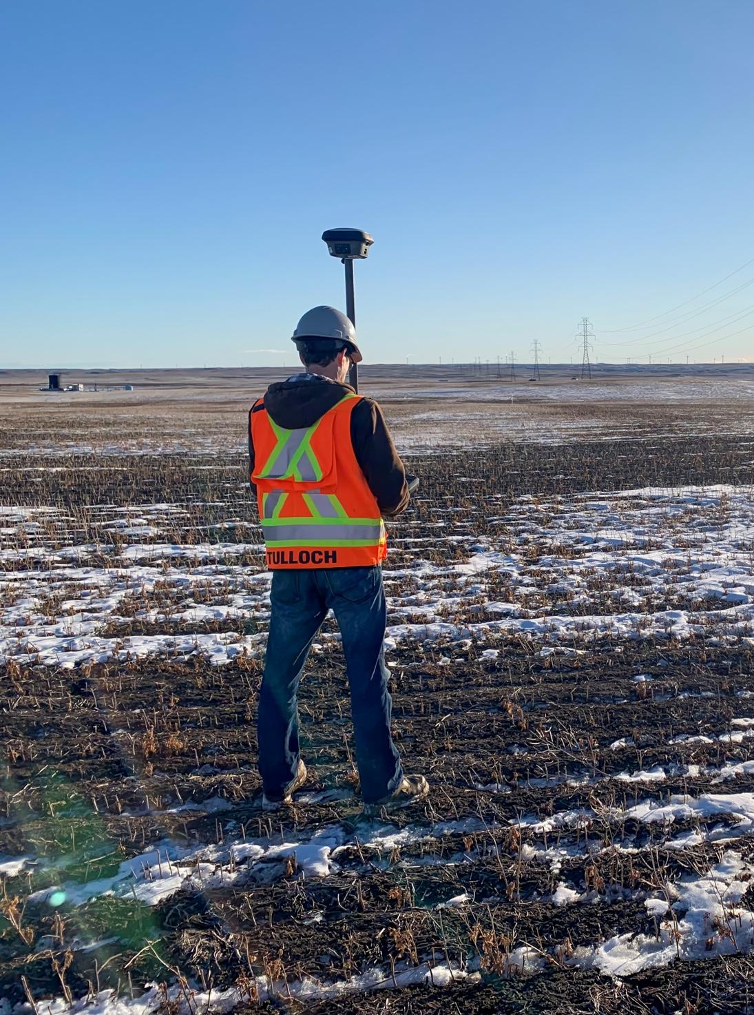 TULLOCH field surveyor collecting data across an open energy project site.
