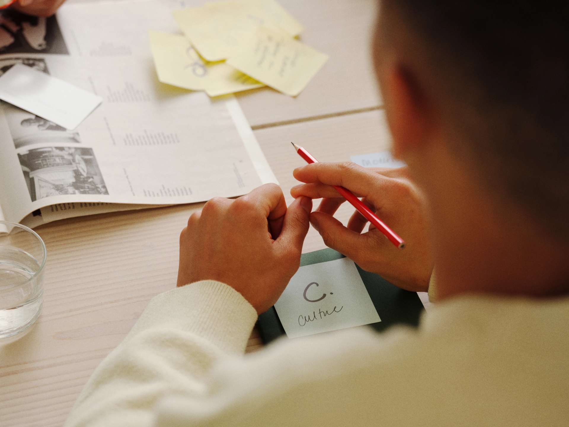 over the shoulder shot of person working at a desk, with pen and papers visible