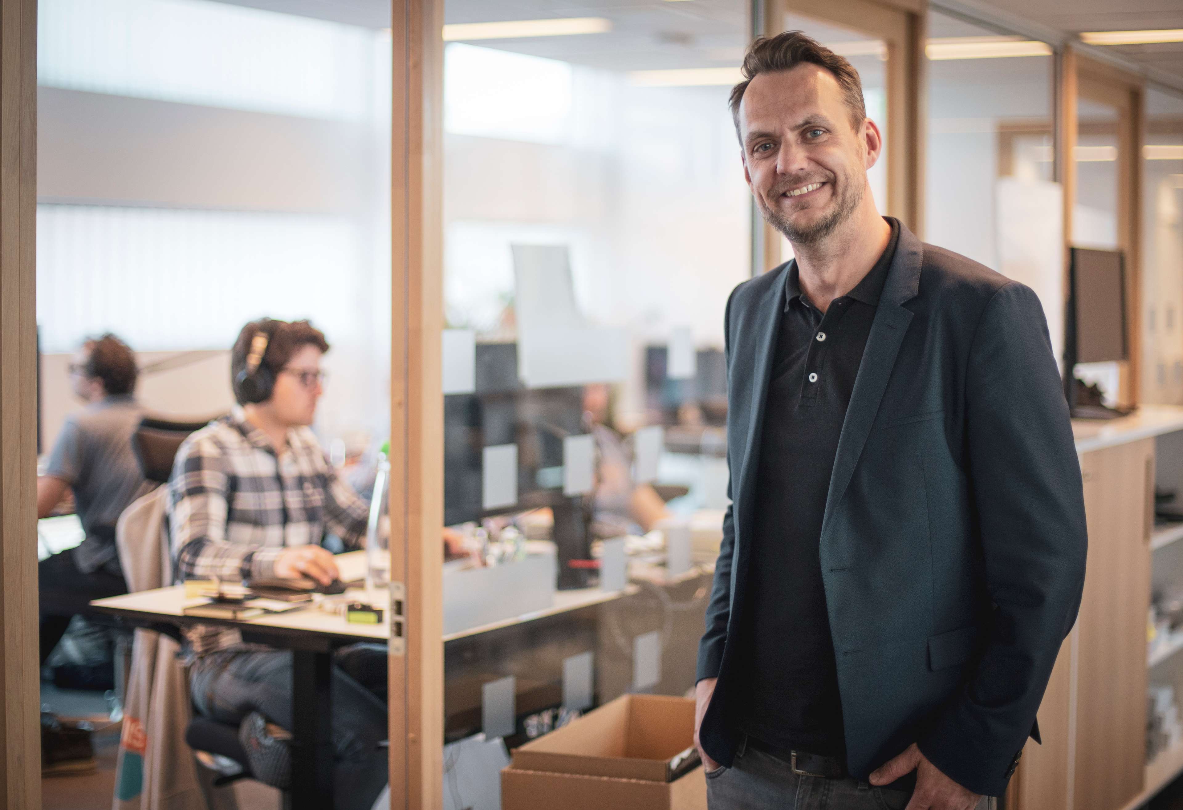 Picture of Vegard Hammer, CTO, in front of an office with people working at their desks