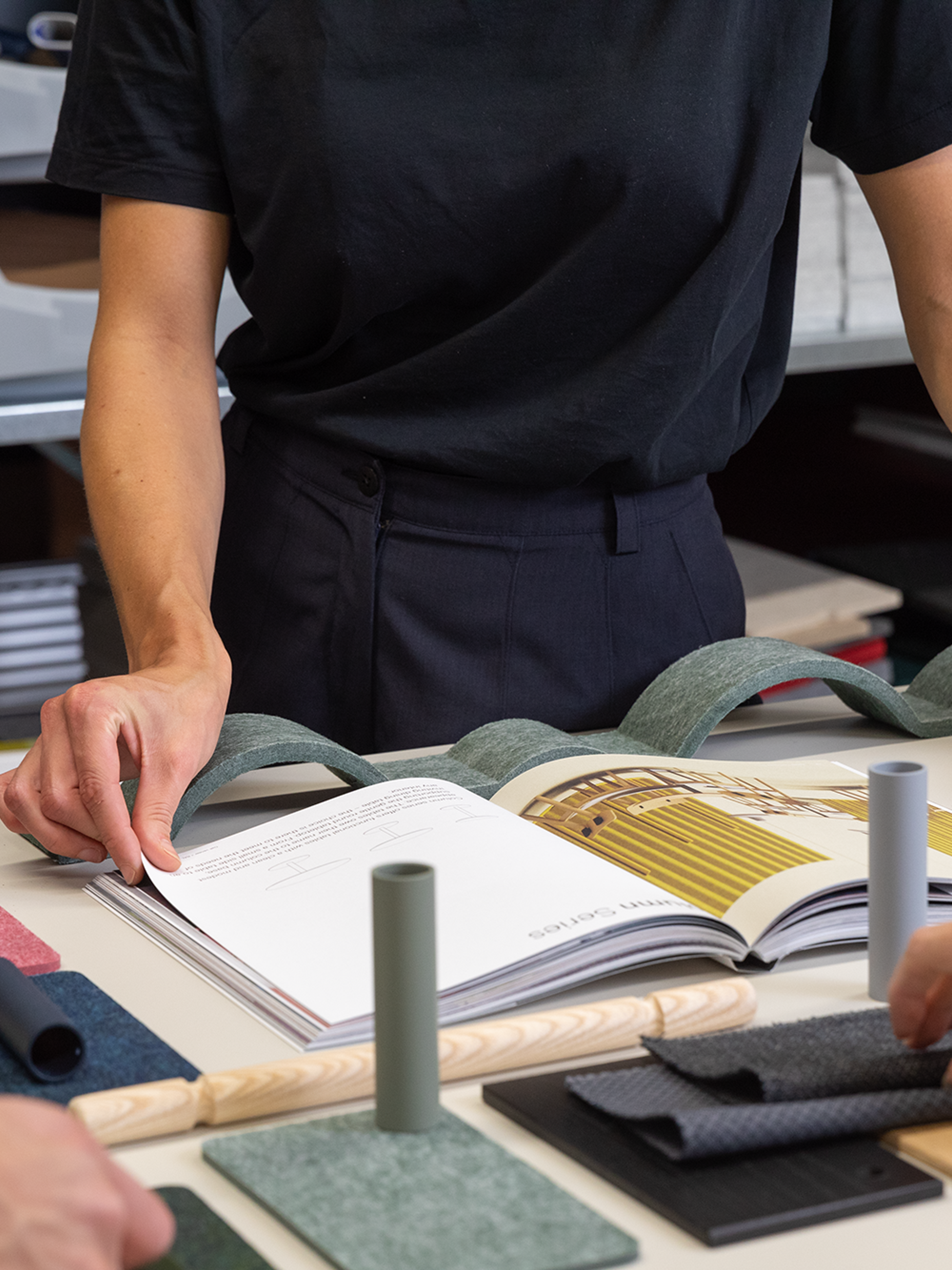 De Vorm design team reviewing PET felt material samples and a product catalogue on a studio worktable