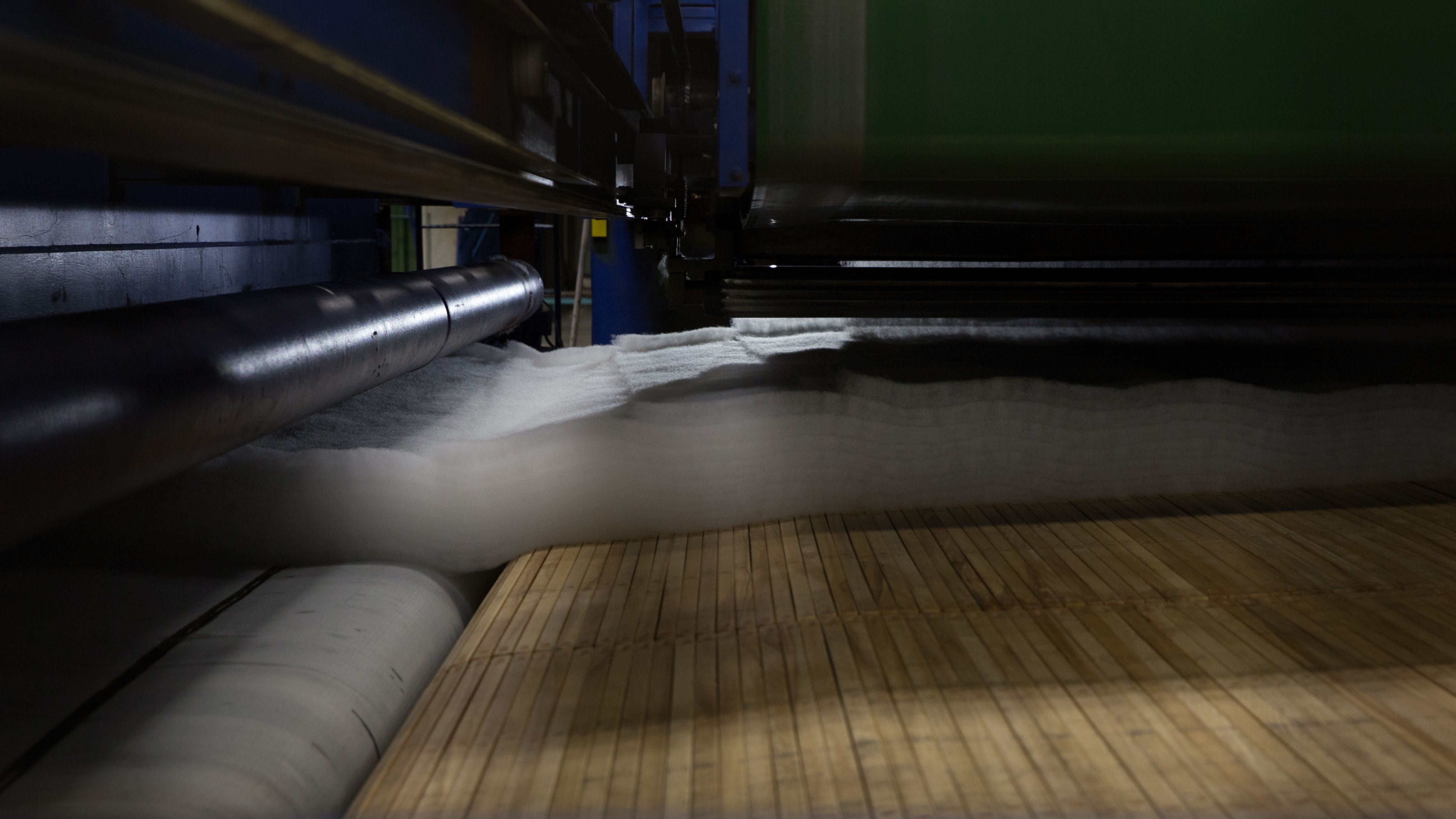 PET felt sheets being compressed and bound by needle-punching machine during the felting process